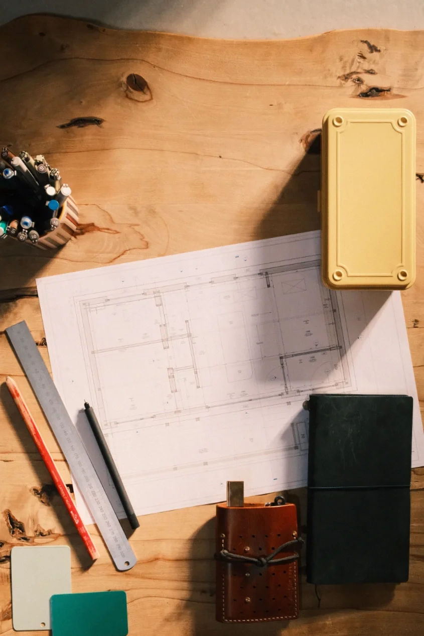 Overhead view of an architects desk with a technical drawing and drawing equipment on it