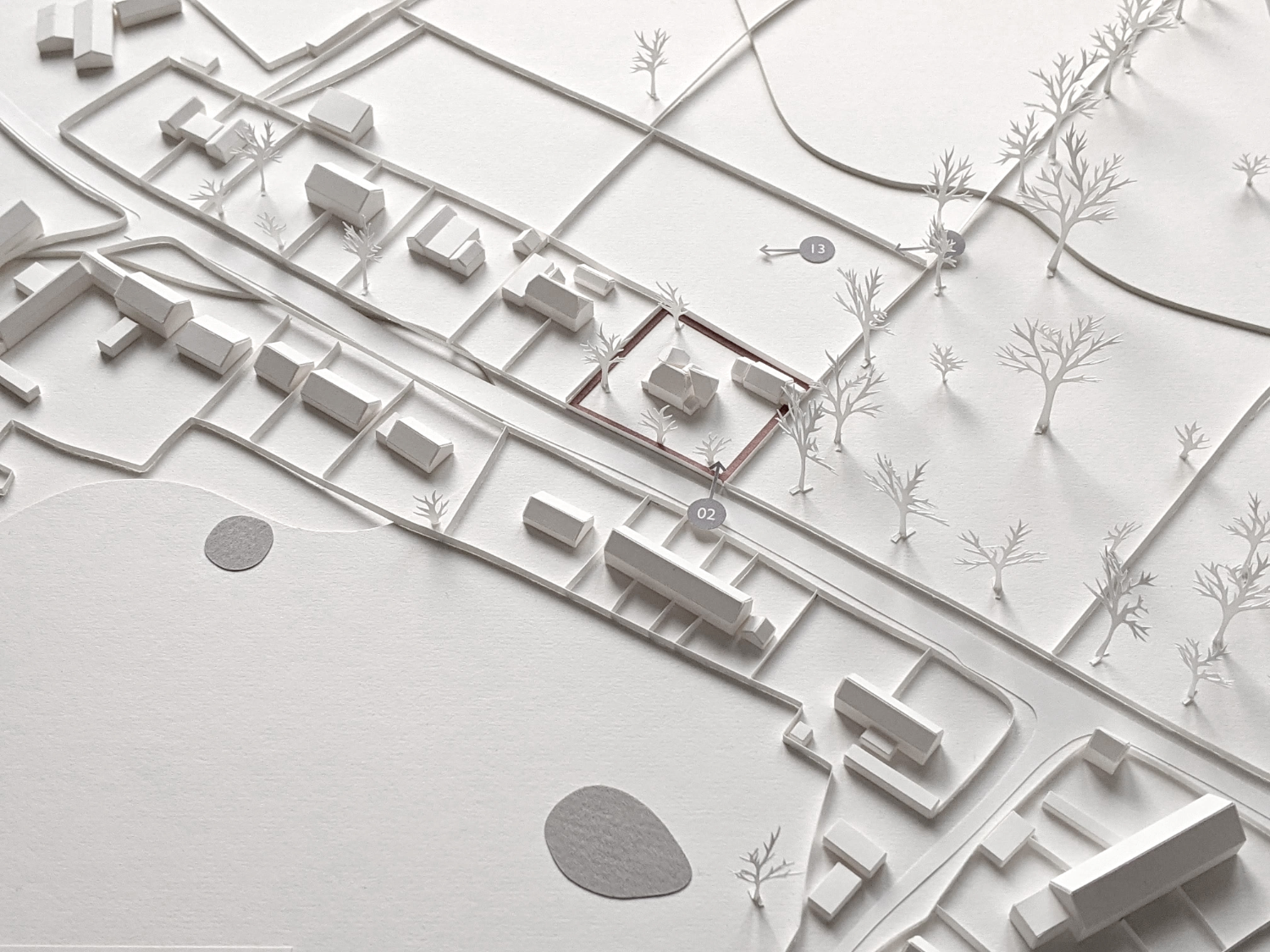 Village modelled in white paper with miniature trees, road and fences