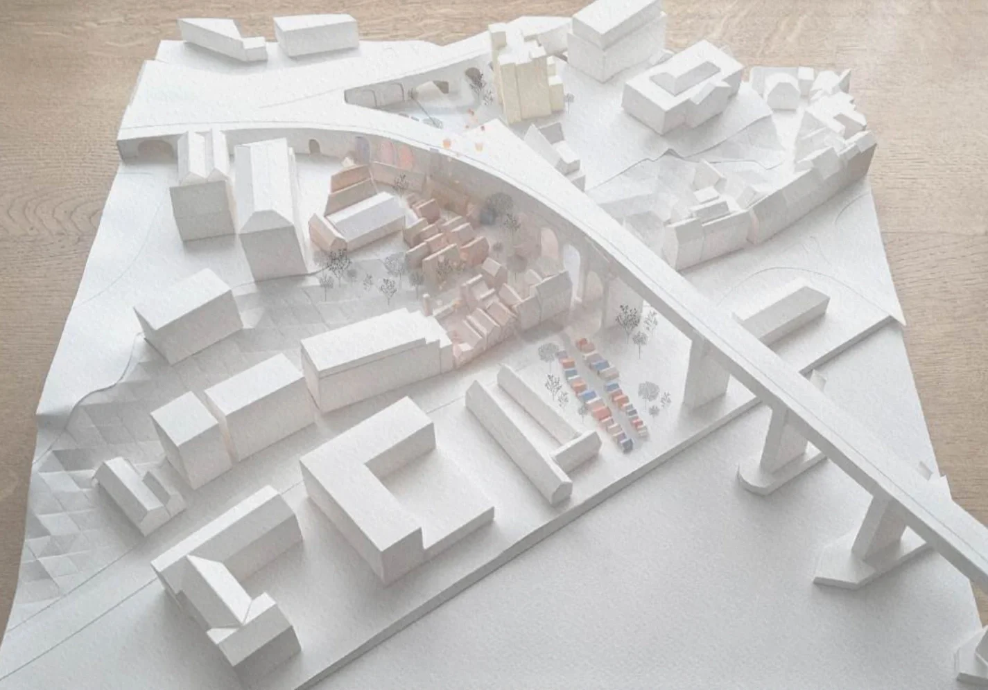 Site model of an urban area with a large curved bridge and river in the foreground