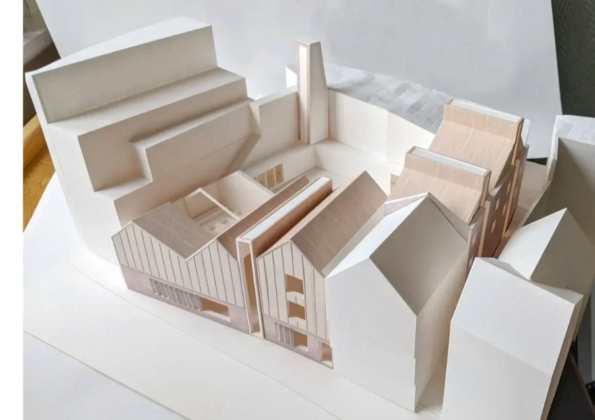 Model of a series of timber clad buildings arranged around a courtyard