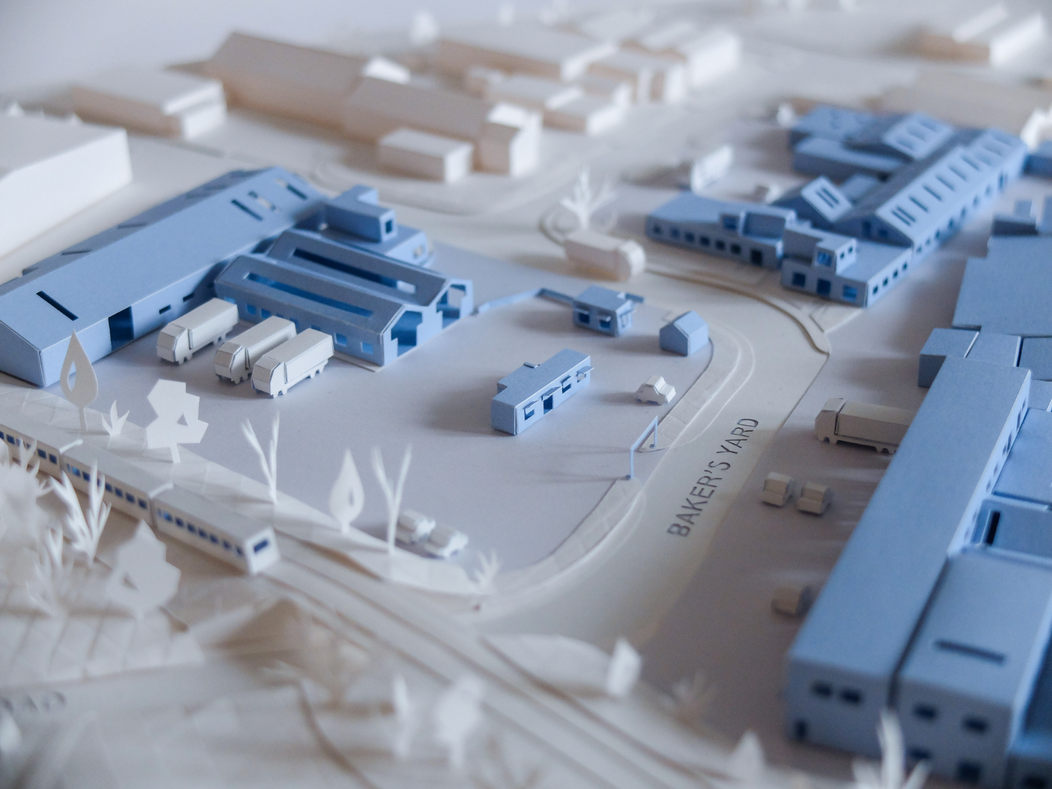 Industrial estate offices modelled in blue paper with miniature white lorries parked outside