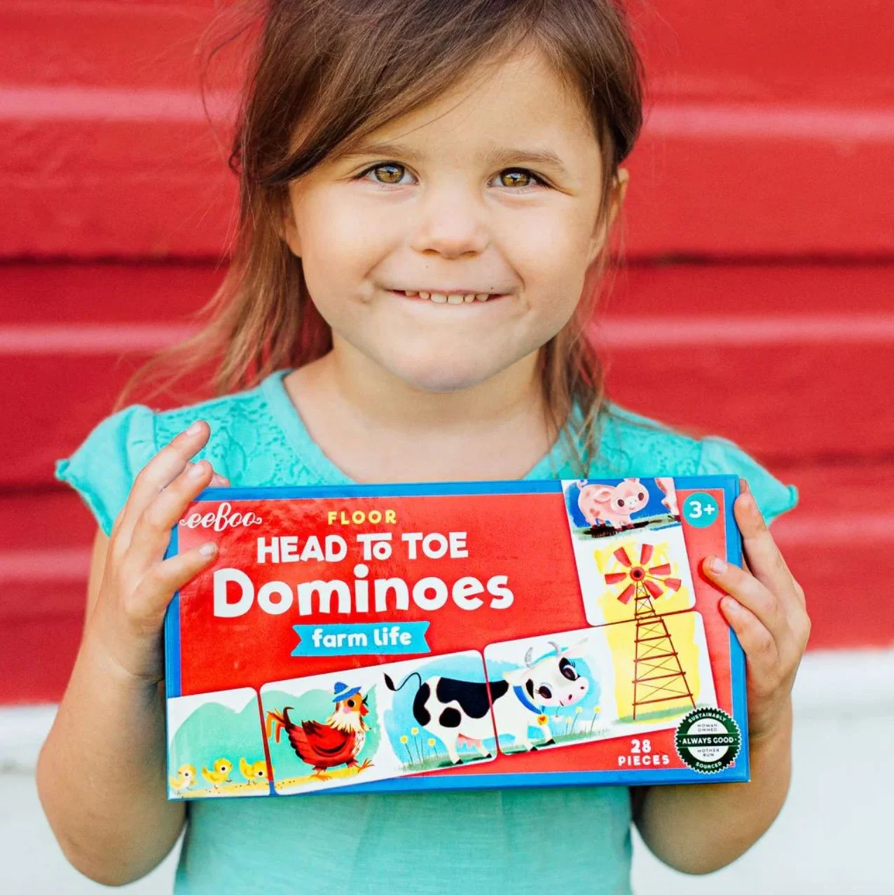 young girl holding a box that says Head to Toe Dominoes: Farm Life