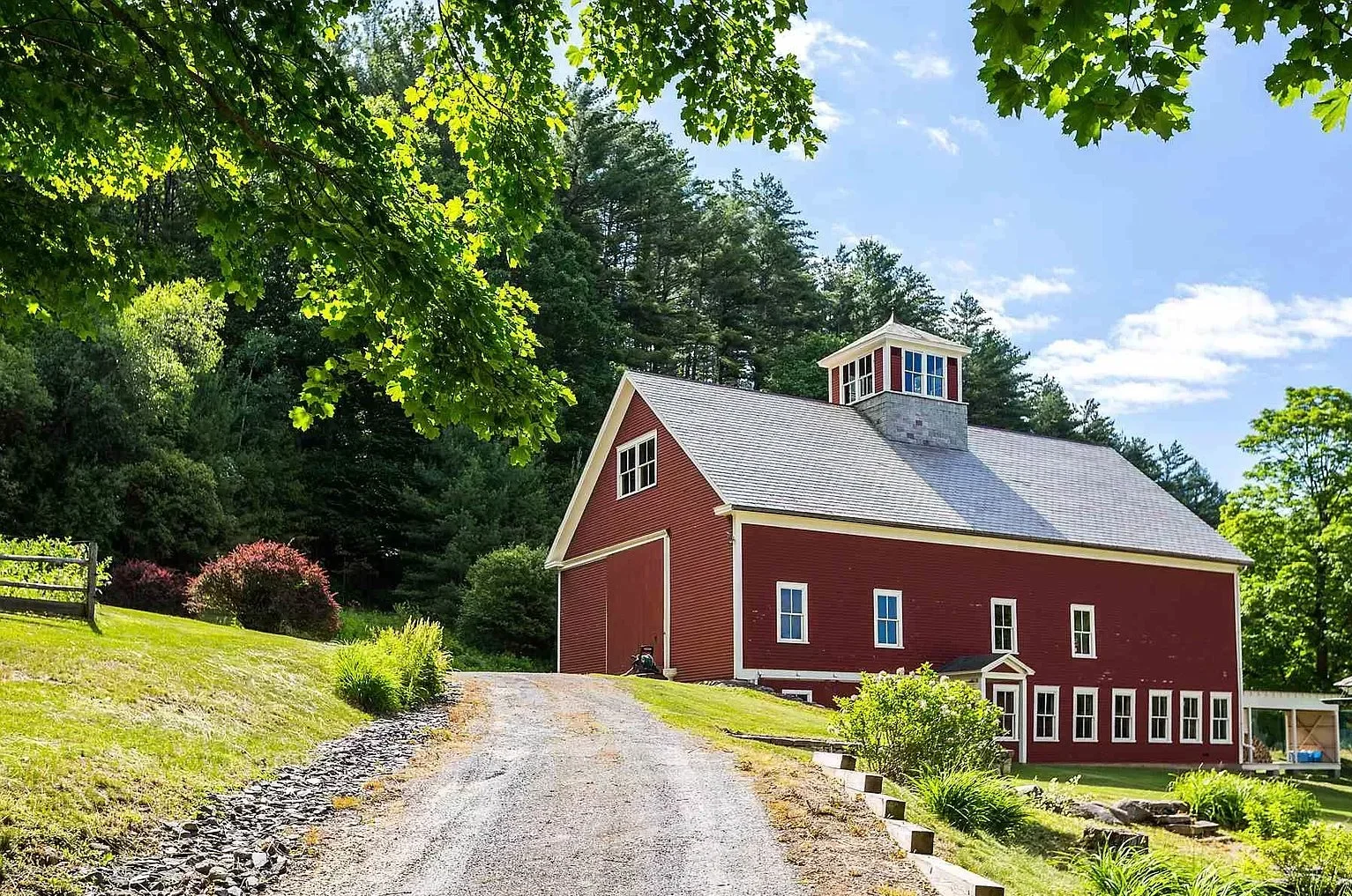 red barn sitting on a green hill