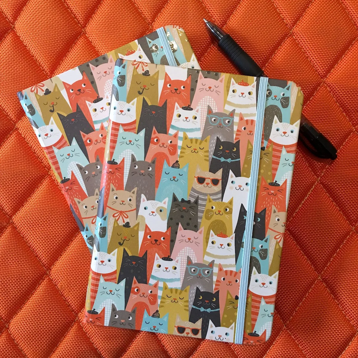 hardbound journal with a cat repeat pattern sitting on quilted orange background