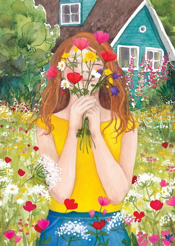 girl in a field of wildflowers holding a bouquet in front of her face