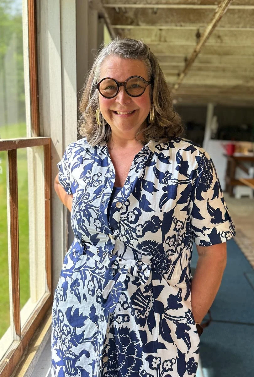 Jennifer Nelson in a floral dress near a barn window