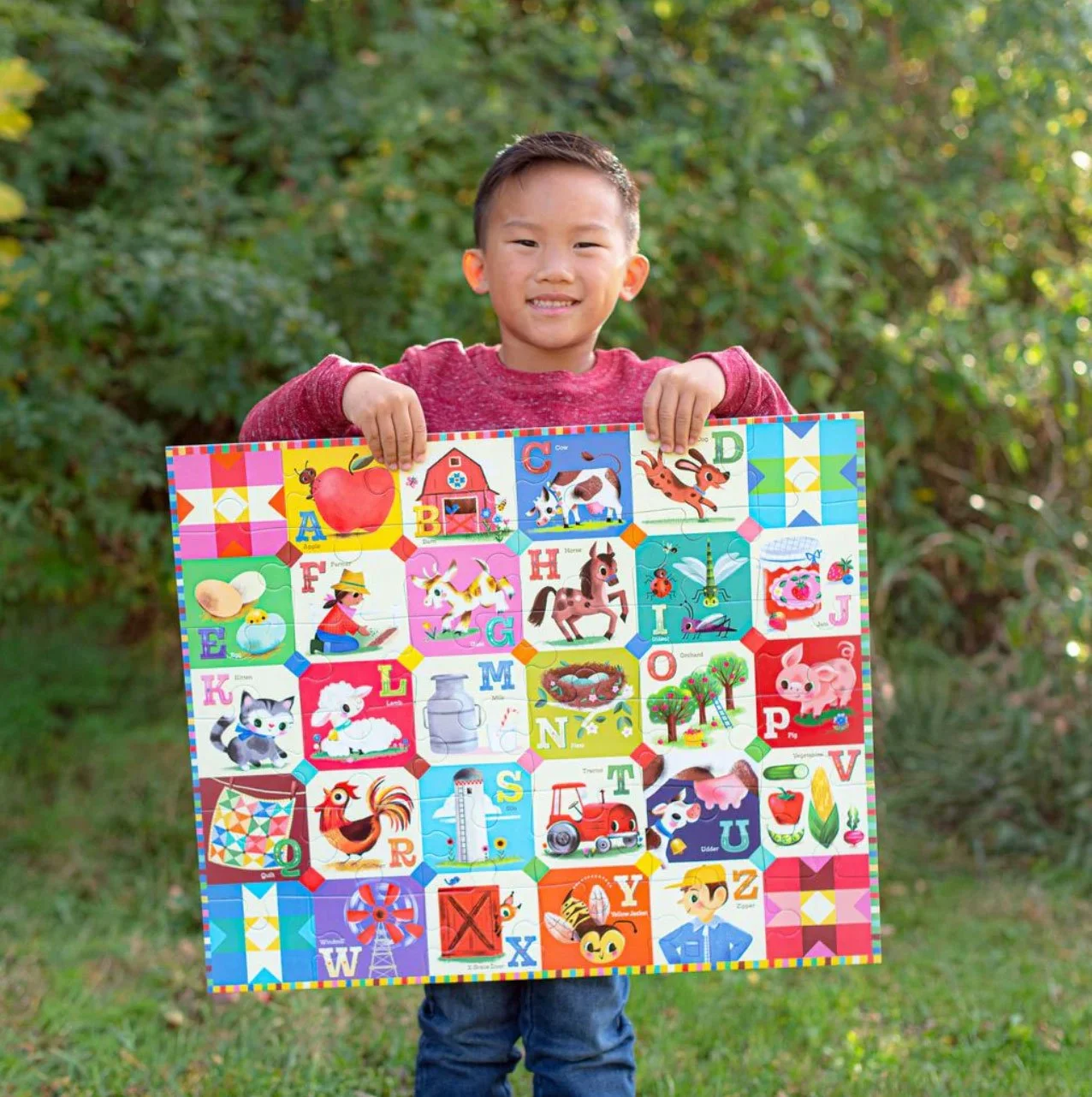 young boy in a green field holding a large farm puzzle