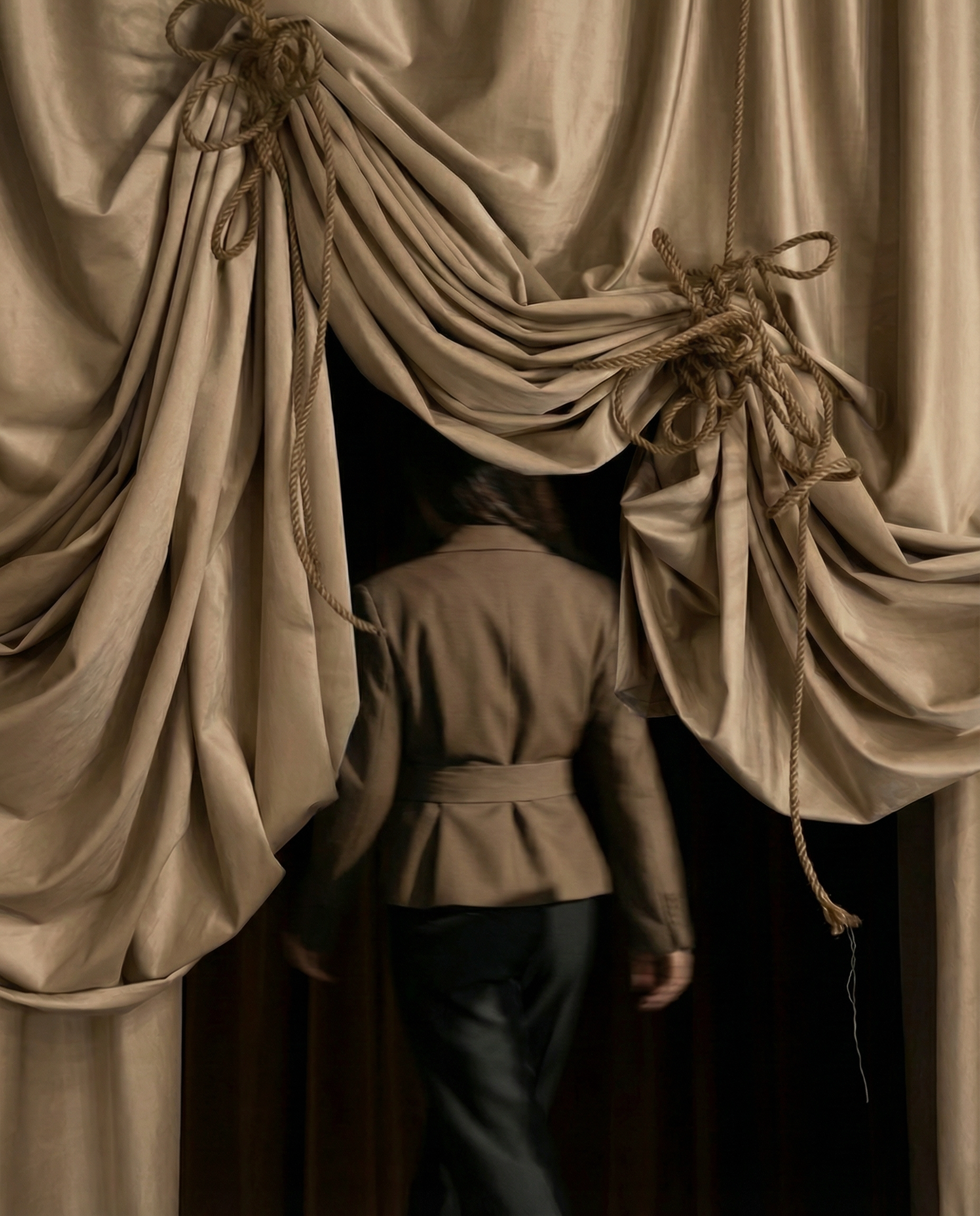 People entering or exiting through a doorway framed by luxurious beige drapes tied with ropes.