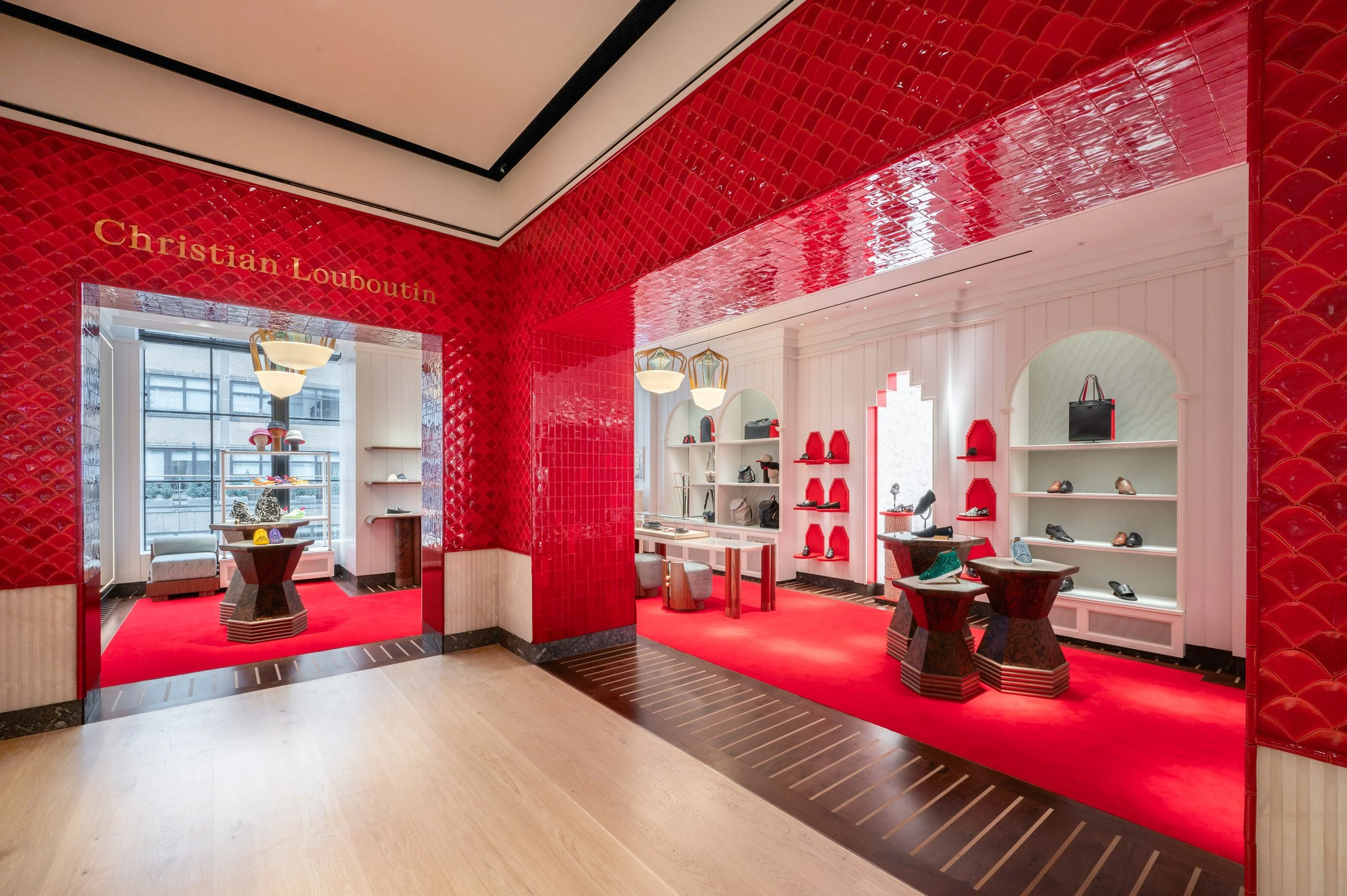 Inside a Christian Louboutin shoe store with red tile walls, white shelving displaying shoes, and a red carpeted floor.