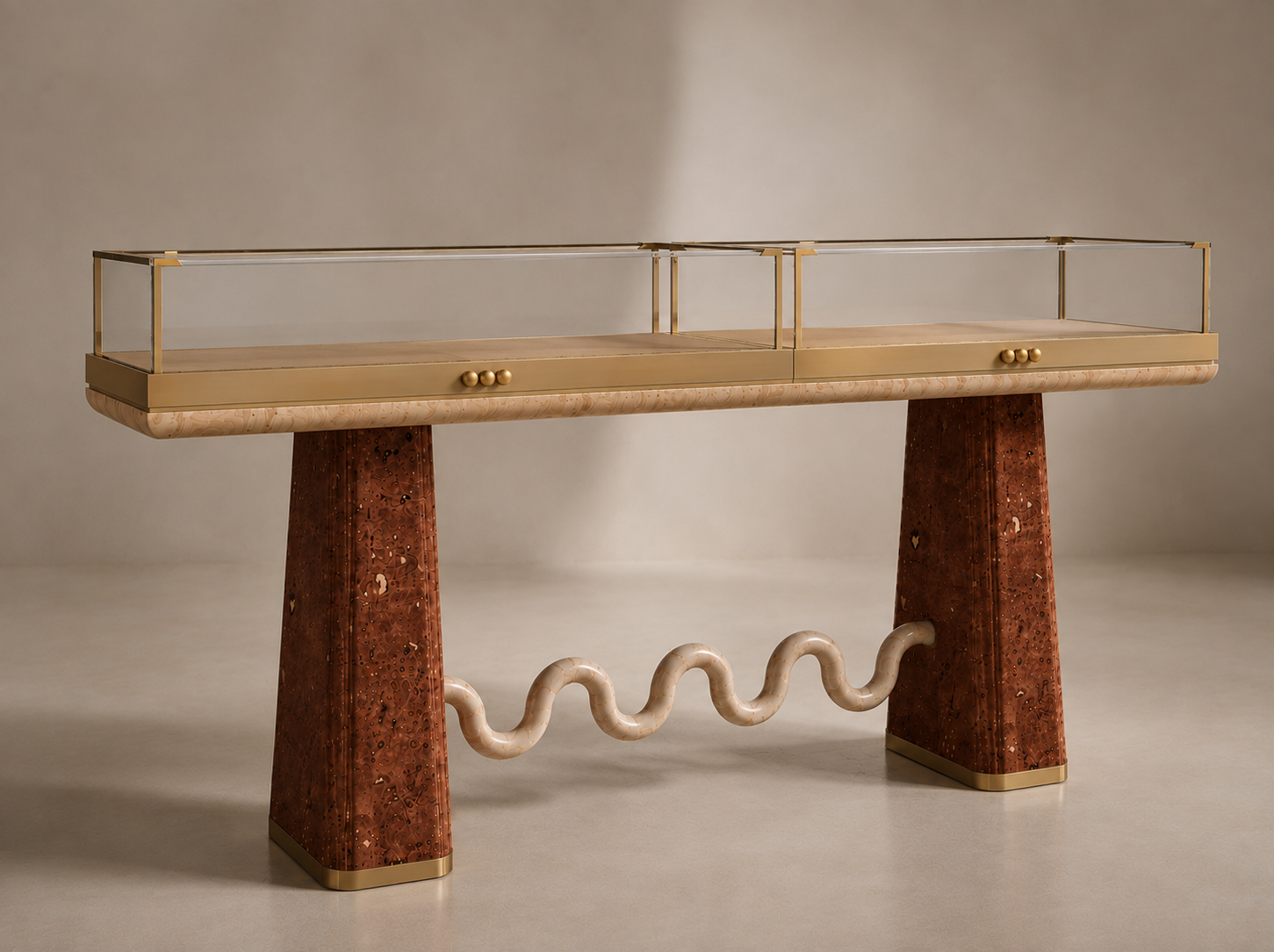 A modern display case with a glass top, brass frame, and oval brass knobs, supported by two large, polished, reddish-brown marble legs connected by a sculptural wavy beige pipe.