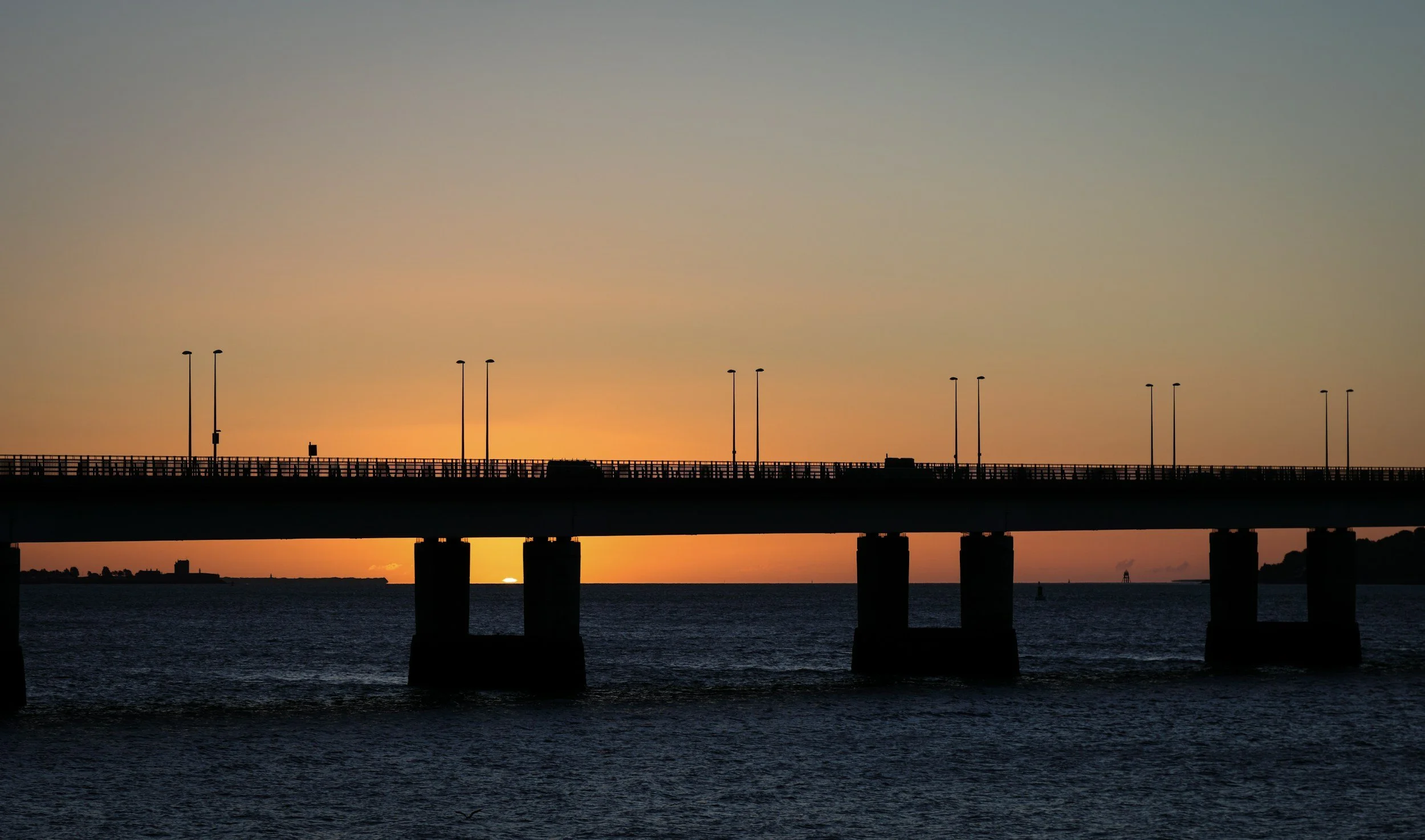Silhouette of Tay Bridge over water at sunset with streetlights along the bridge, Sakura Property Collective, estate agents in Dundee & St Andrews.