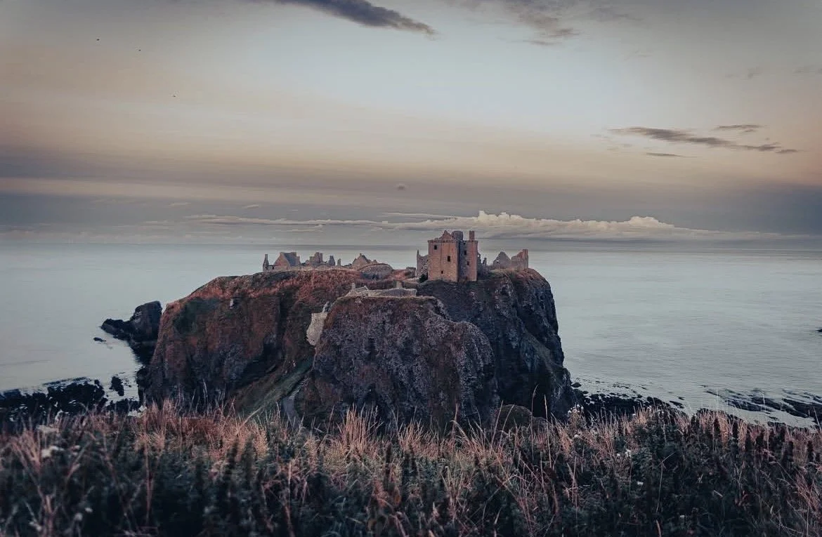 Dunnottar Castle on a rocky cliff overlooking the ocean at sunset, photographed by Kaelyn Robertson Sakura Property Collective, estate agents in Dundee & St Andrews.