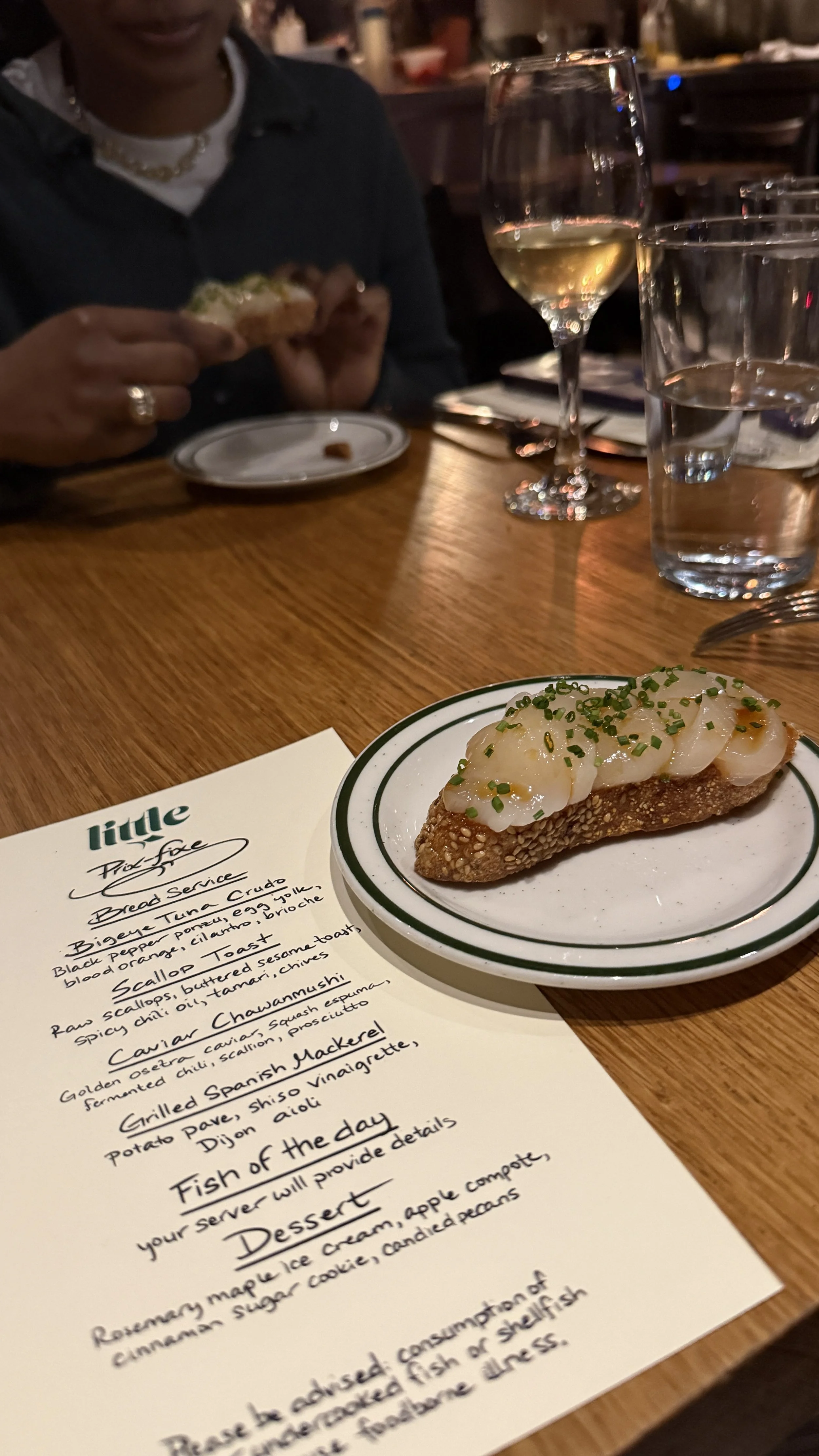 One of Little Fish's popular dishes, scallop toast. Made with raw scallops topped with chopped chives on a sesame seed-crusted toast.