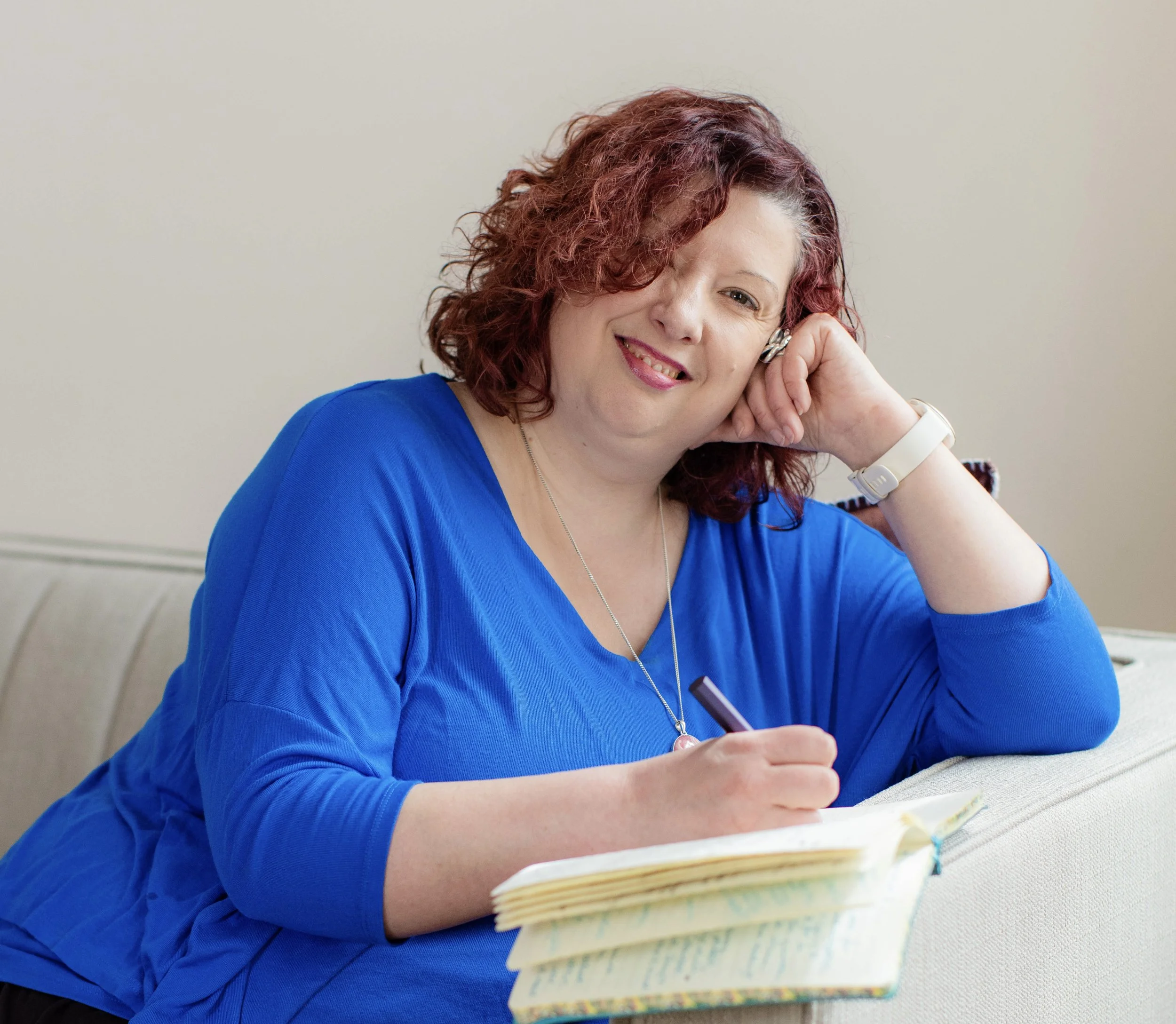 Photograph of Beth Roberts, trauma informed counsellor in Oxford, UK.  Beth is smiling and writing.