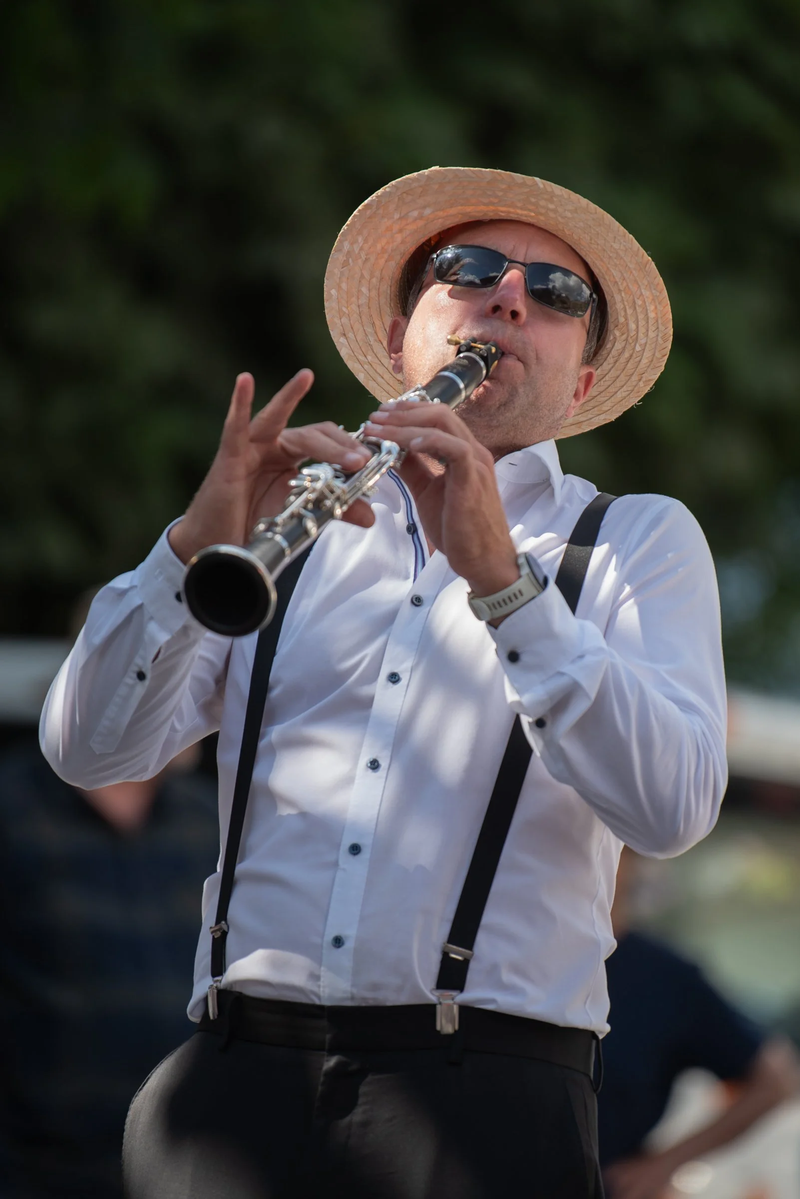 Mann spielt auf einer Klarinette, trägt Sonnenbrille, Strohhut und Hemd.