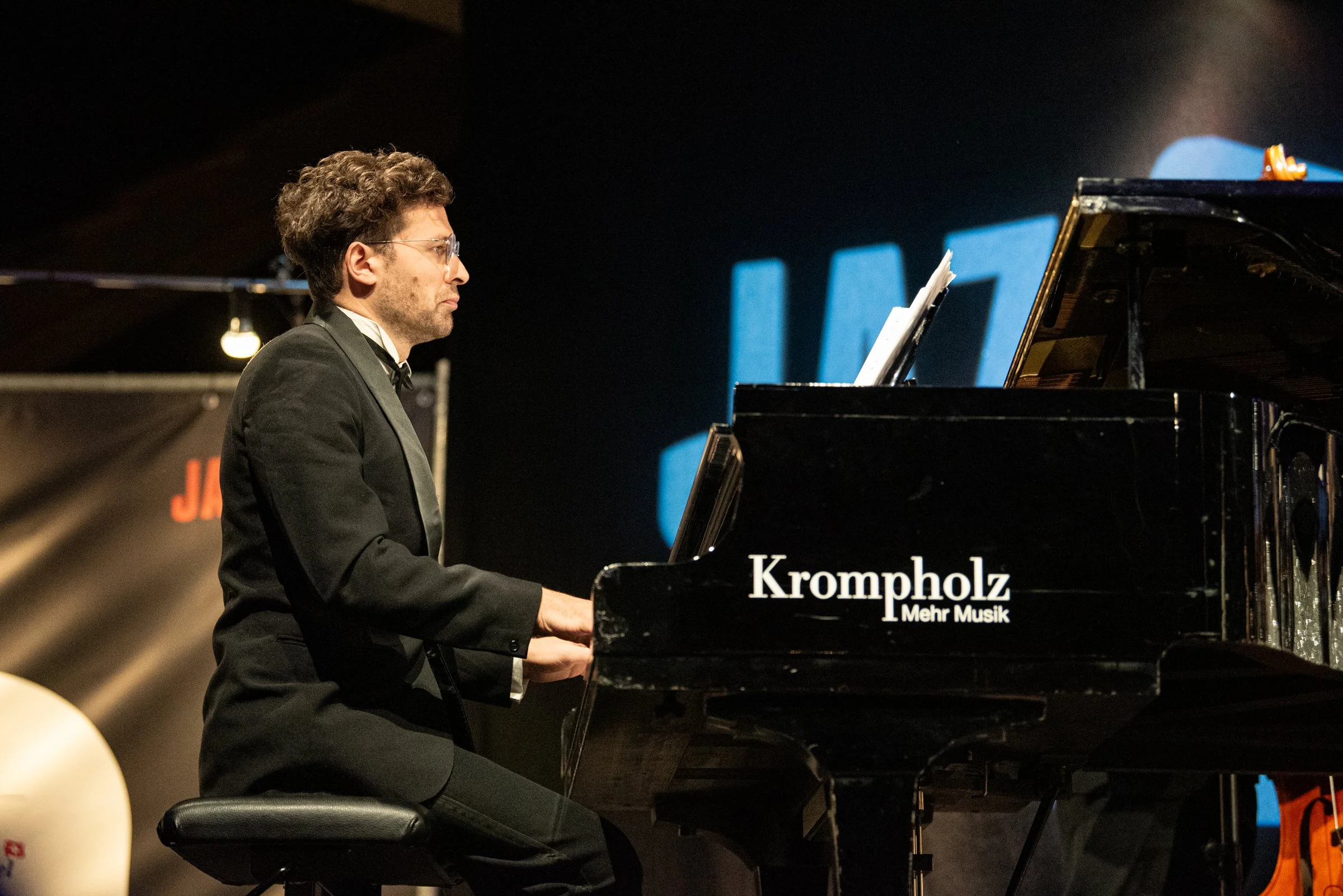 Ein Mann spielt Klavier auf einer Bühne bei einem Konzert.