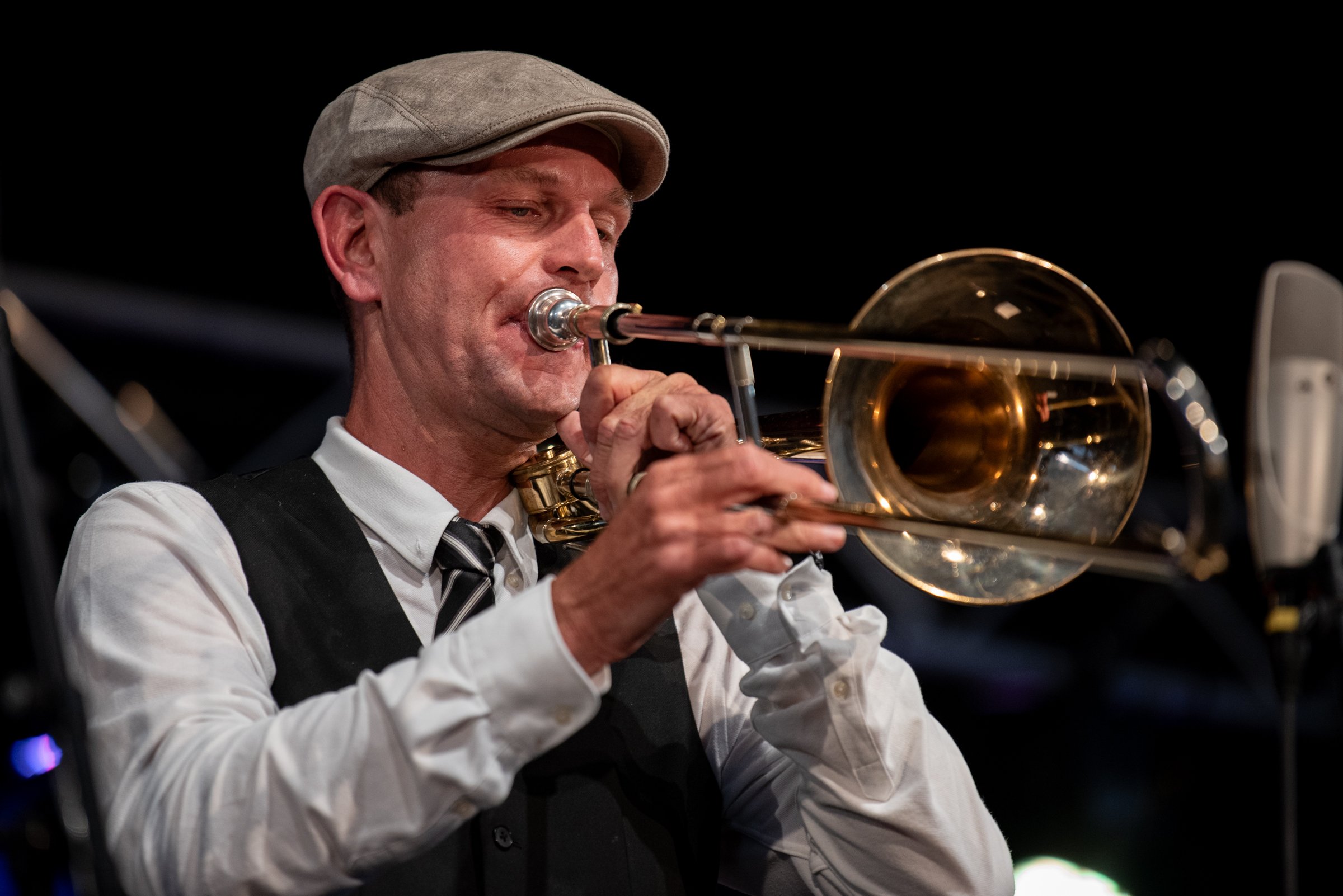 Ein Musiker spielt Trompete auf einer Bühne bei einem Konzert.