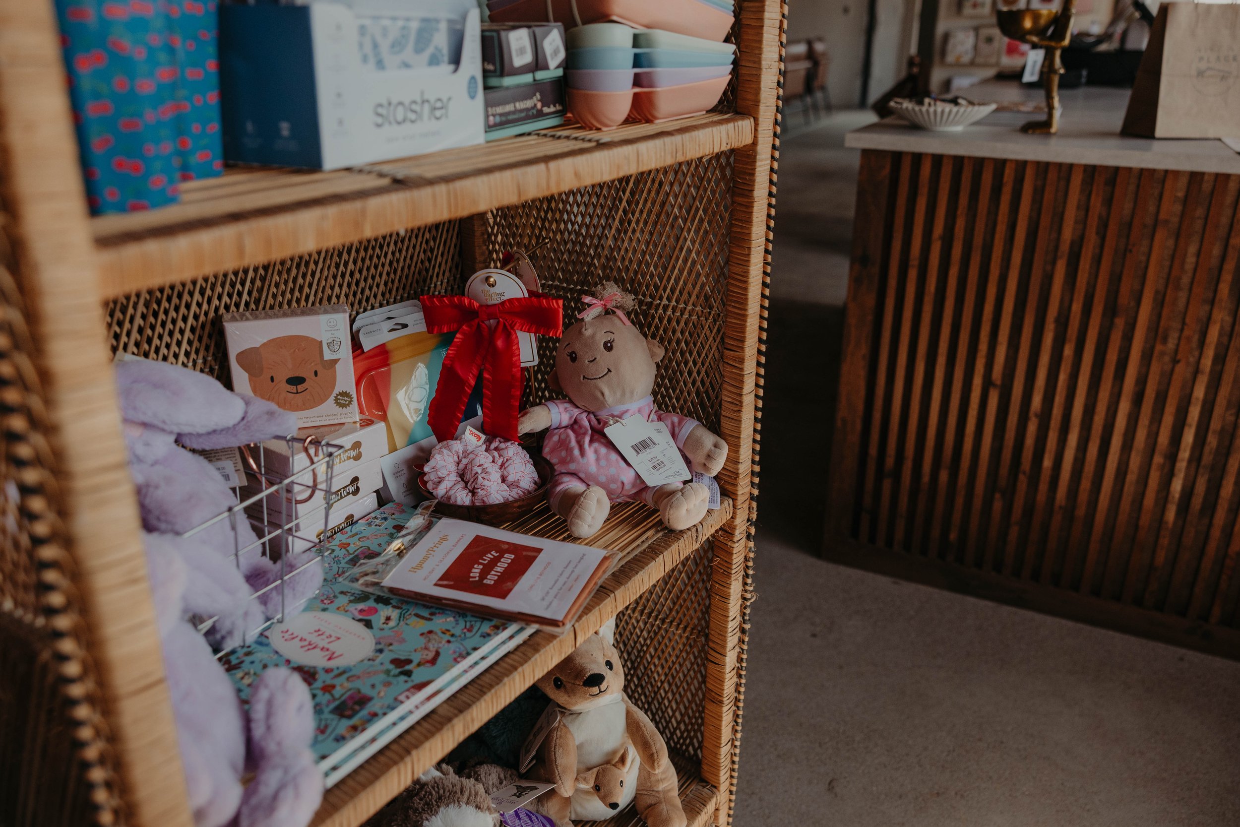 Wicker shelf with colorful bowls, stuffed animals, and various small items in a store.