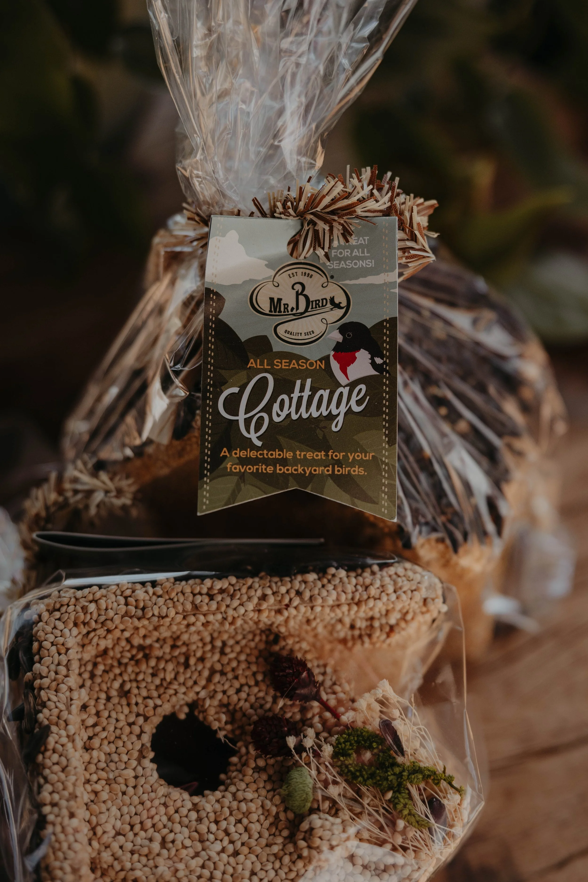 Close-up of a seed gift bag with a Tag that reads "Mr. Bird" and contains mixes of seeds, possibly for backyard birds, with decorative dried flowers and berries.