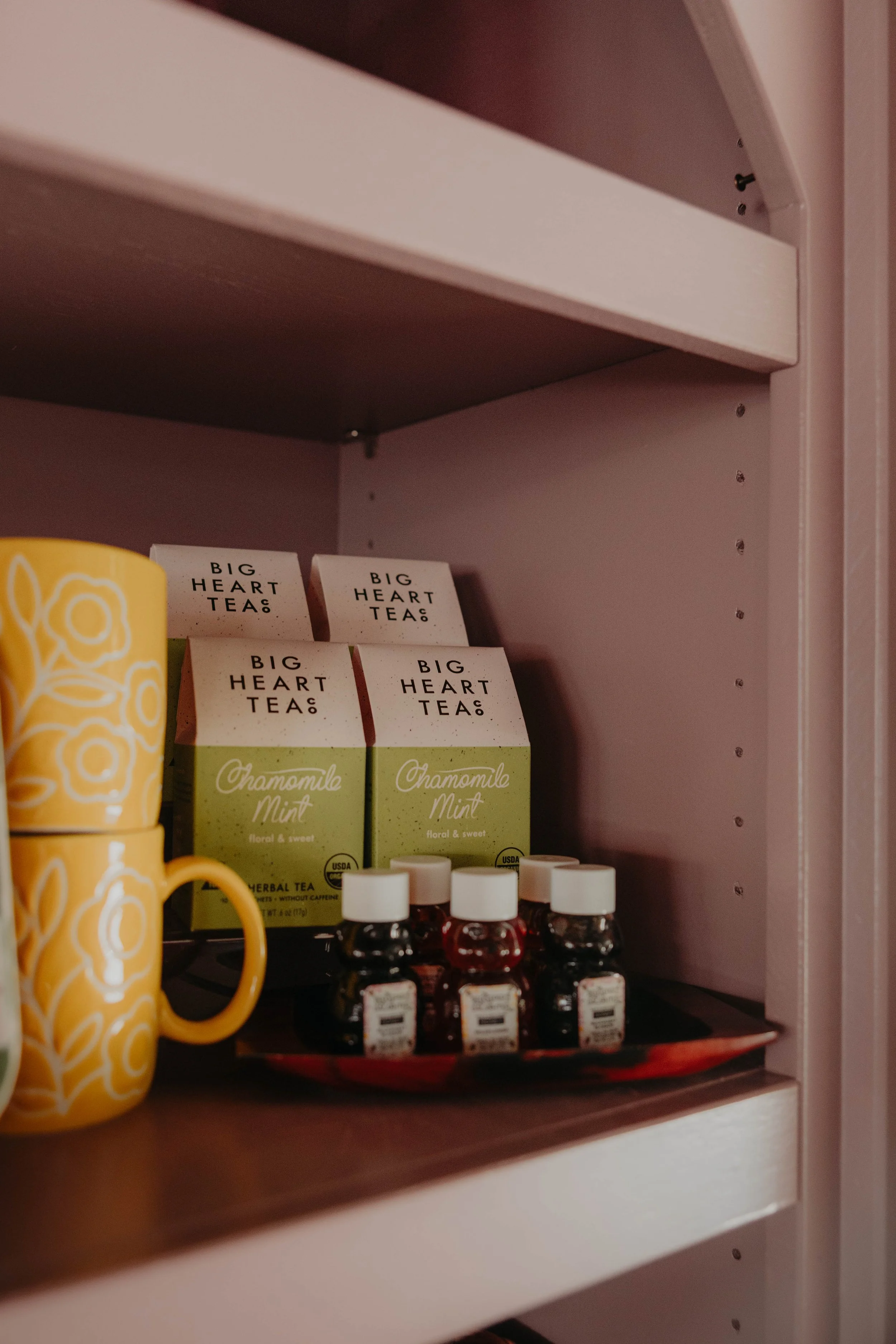 A shelf with boxes of Big Heart Tea Chamomile Mint herbal tea and small bottles of essential oils.