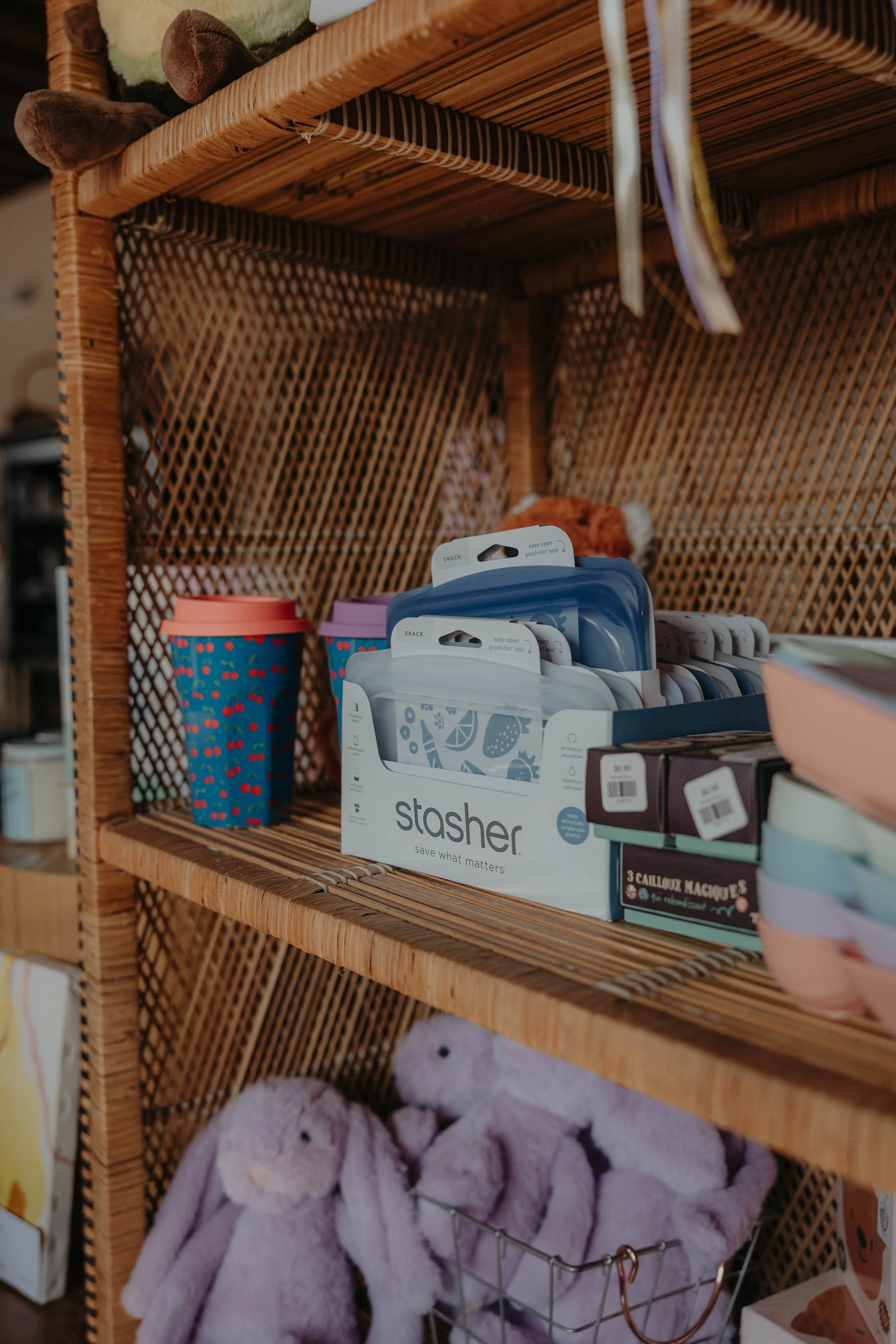 Wooden shelf with stuffed animal, colorful cups, and storage box with blanket or plush toys.
