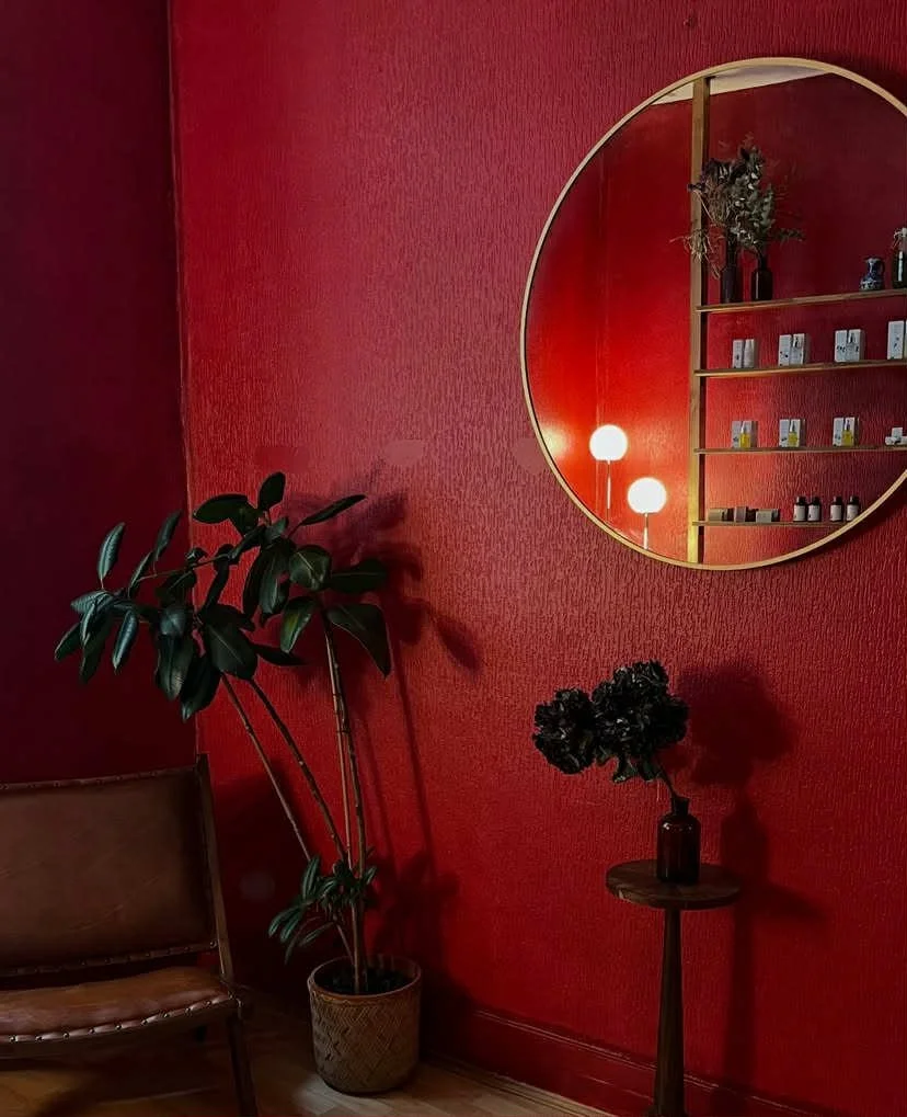 Intérieur très cosy avec mur rouge, miroir rond, plantes vertes et accessoires de décoration.