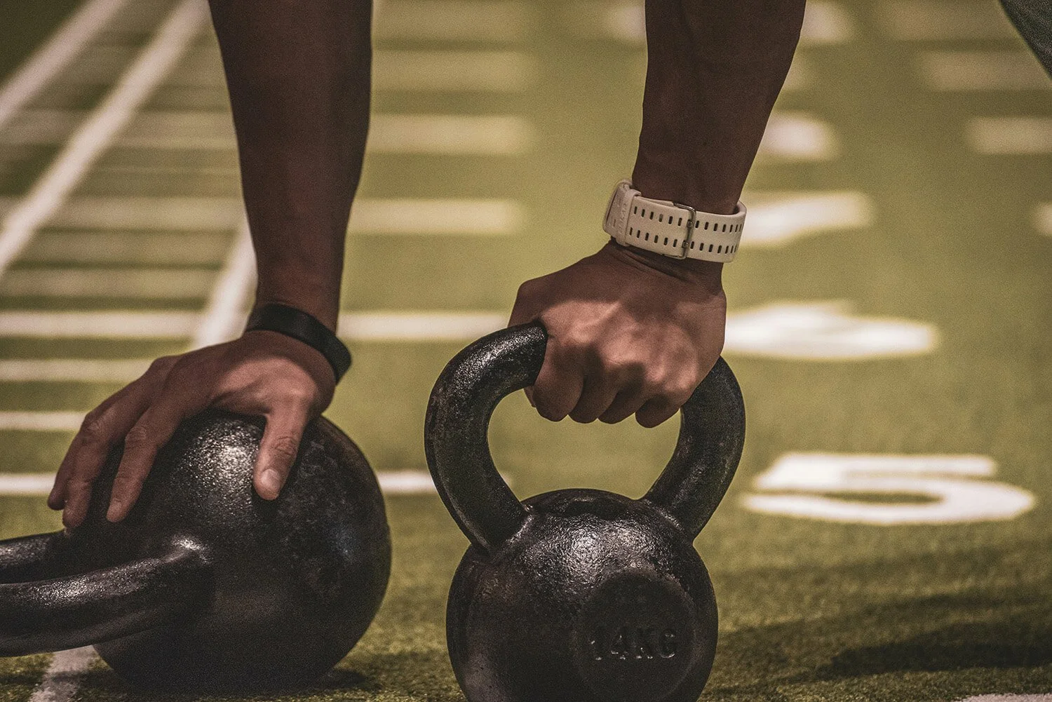 Zwei kräftige Männerhände greifen zwei Kettlebells beim Krafttraining