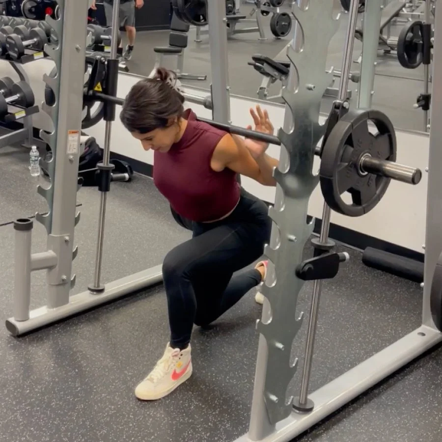 Francesca performing split squats on a Smith machine during lower-body strength workout