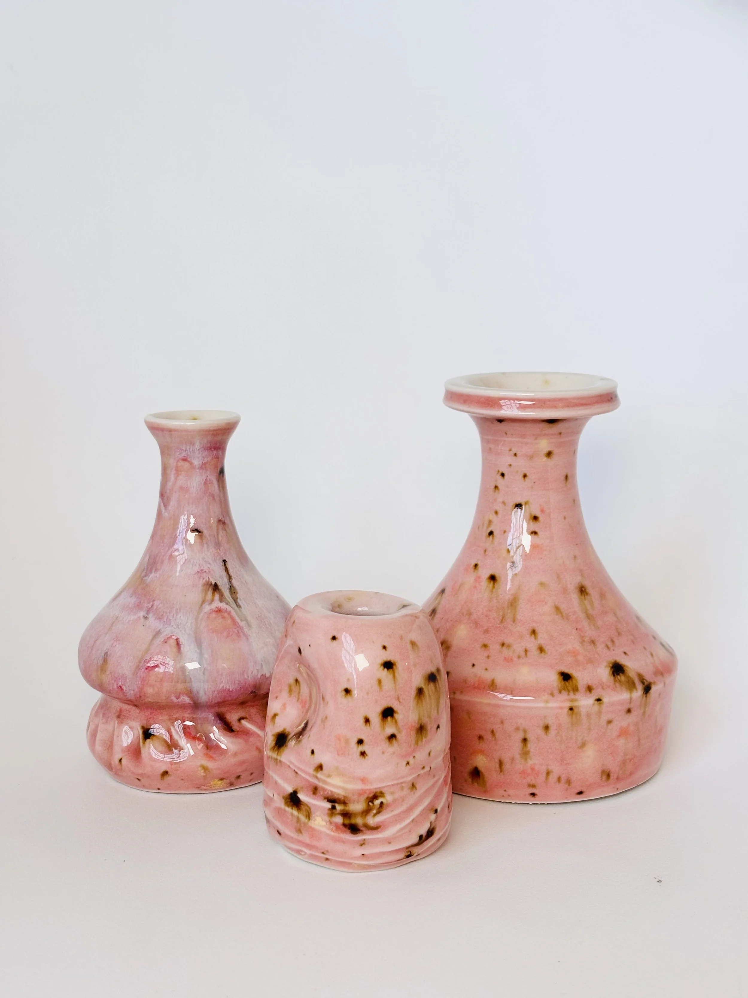 Three pink ceramic vases with a speckled and marbled pattern, set against a plain white background.