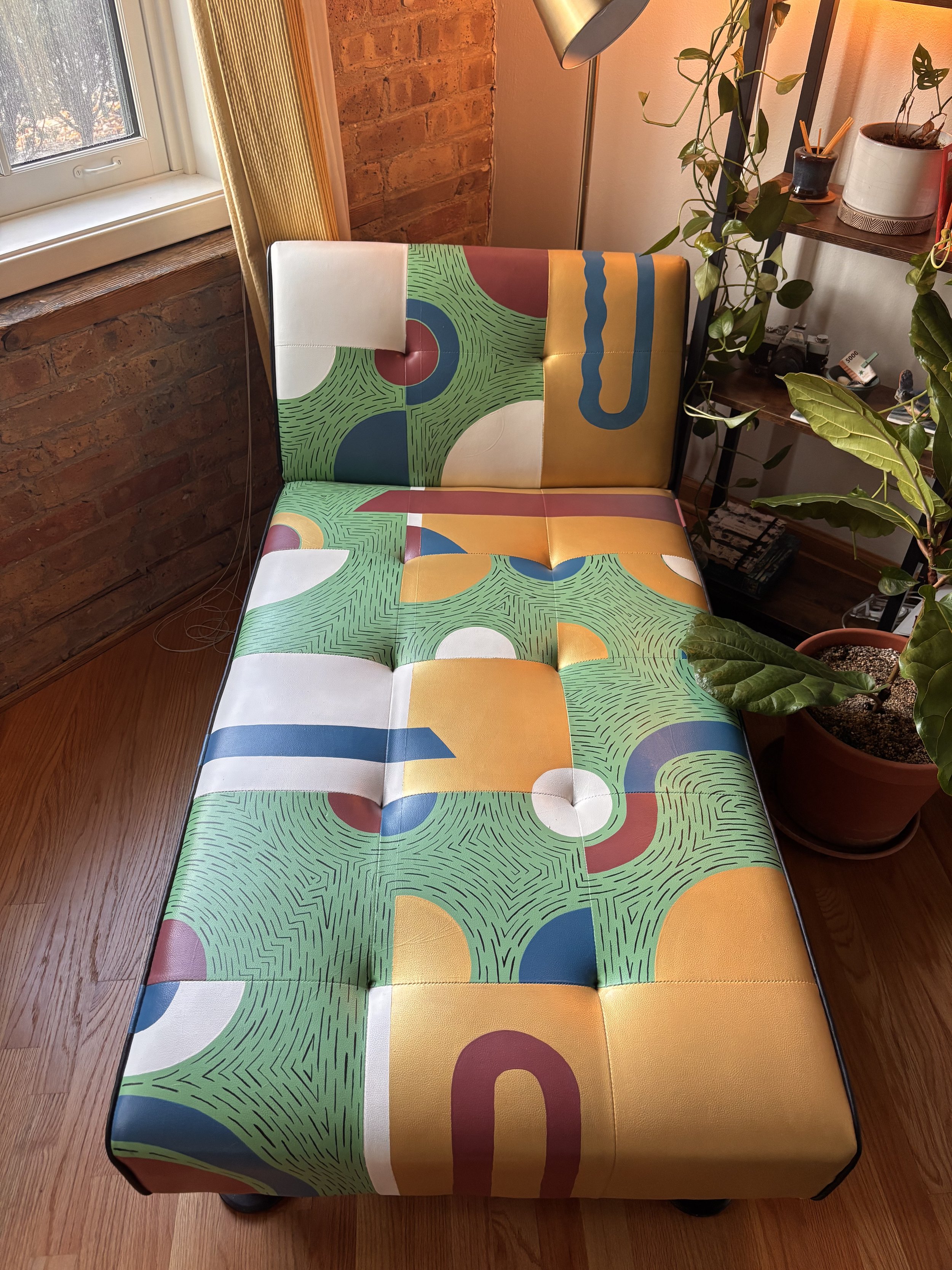 Colorfully painted leather on a modern lounge chair with a patchwork design of various colors and shapes. Custom furniture painting. 