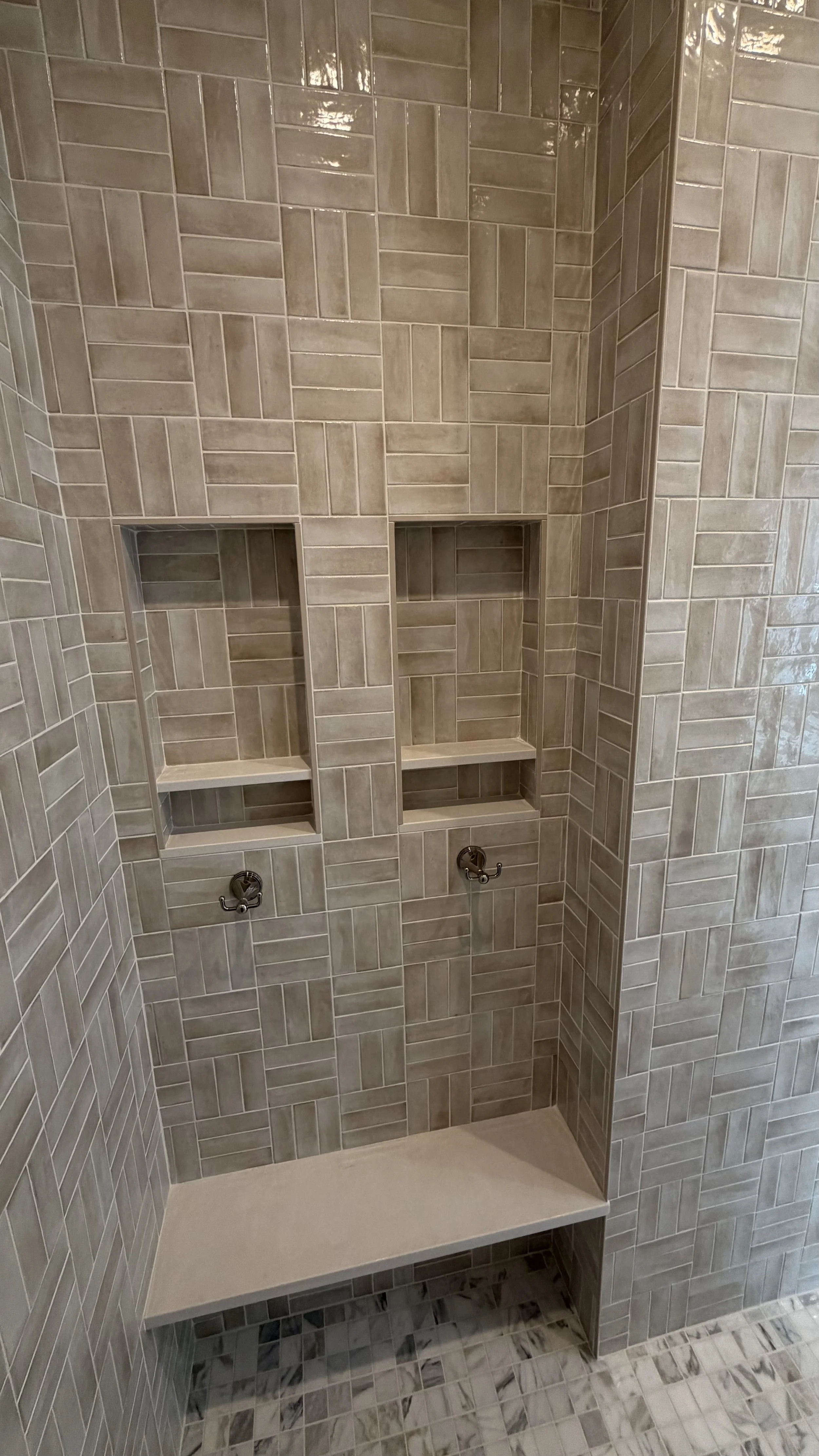 Shower with beige tiles, built-in shelves, and two visible water supply fixtures.