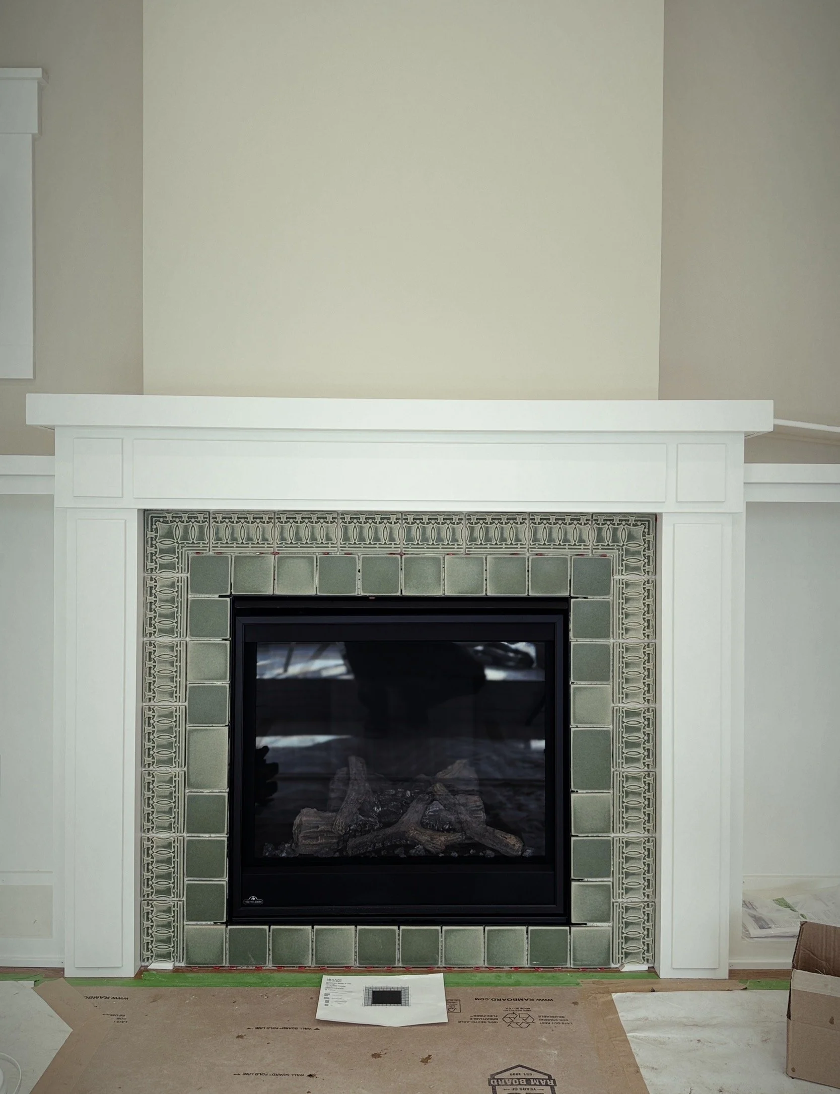 Fireplace with green tile surround and white mantle, under construction or renovation.
