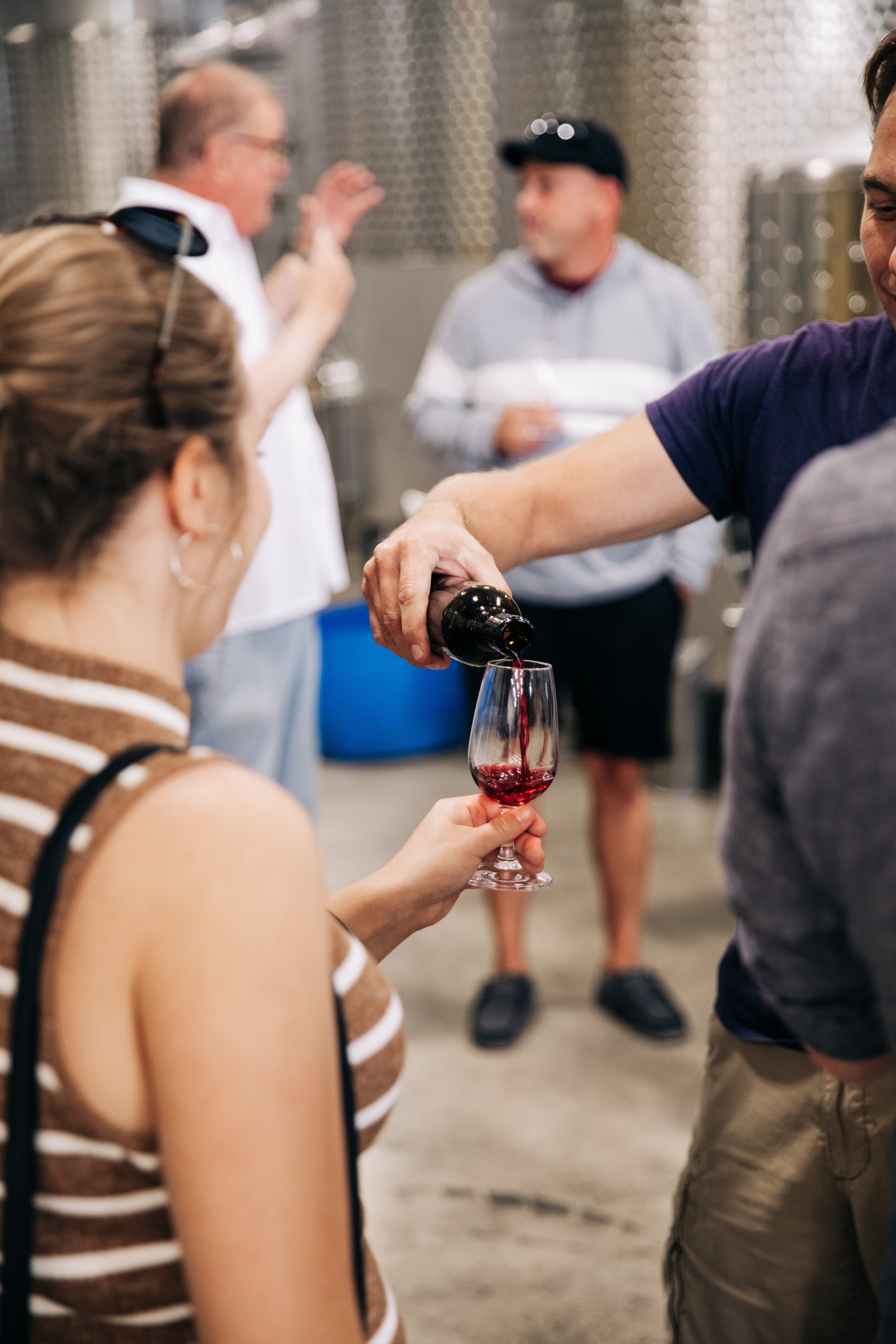 Someone pouring wine into a glass for a guest