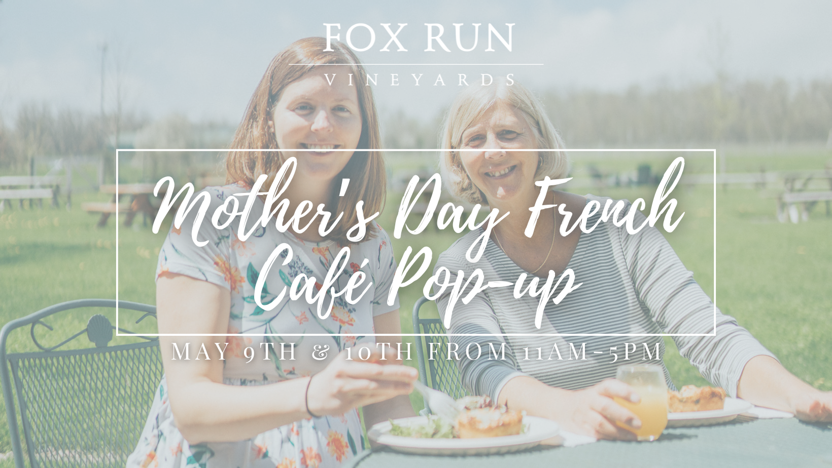 Two people sitting at a table smiling and enjoying food and a drink