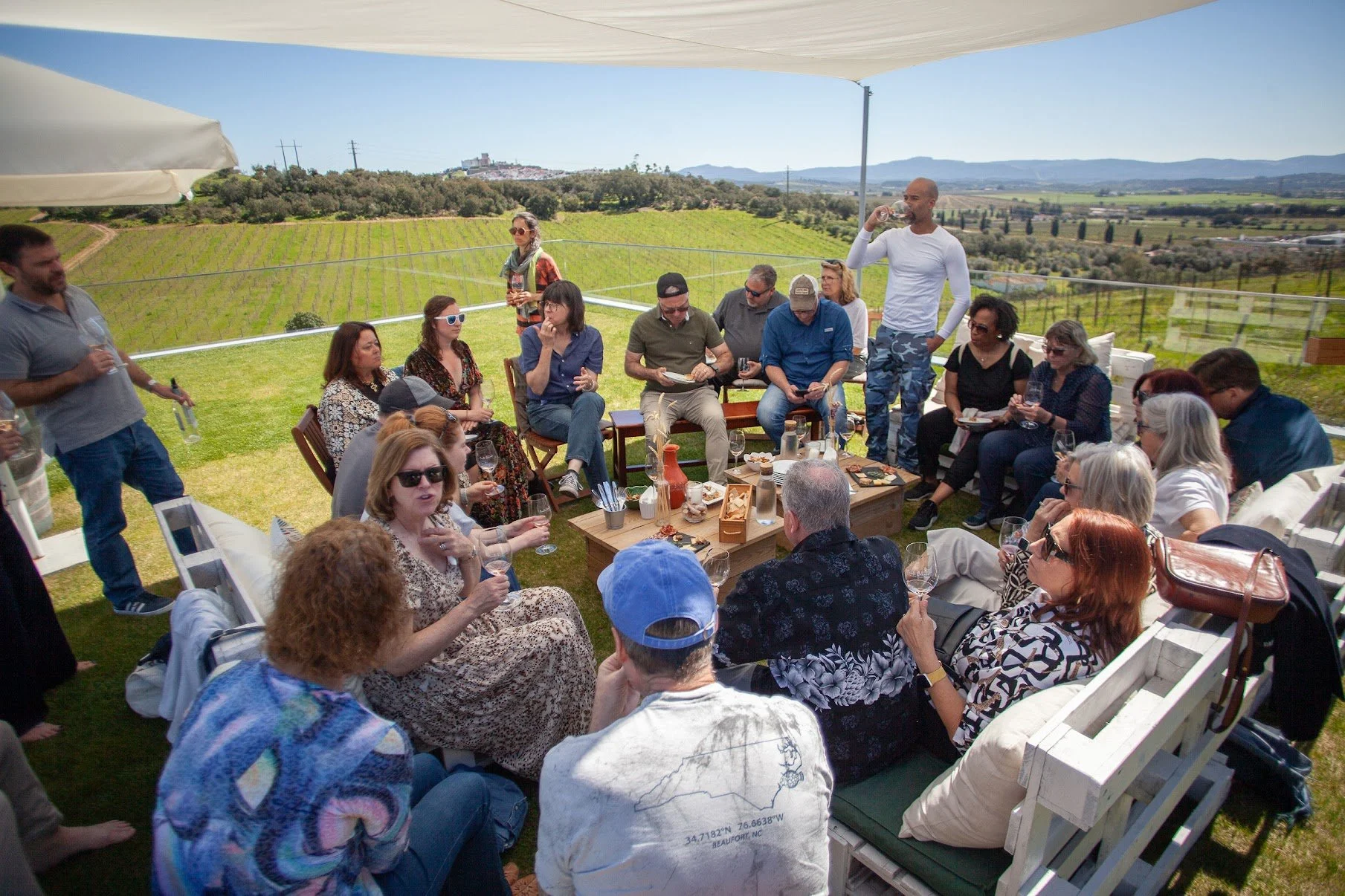 people sitting around tables eating food and drinking wine