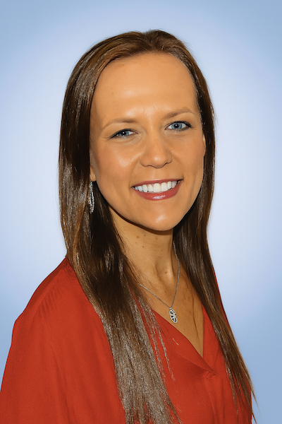 A woman with long brown hair wearing a red top, smiling, with a light blue gradient background.