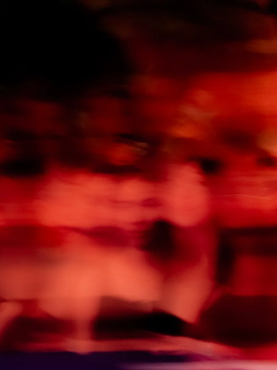The image is very blurry and contains red and black colors, making it difficult to identify specific objects or subjects.