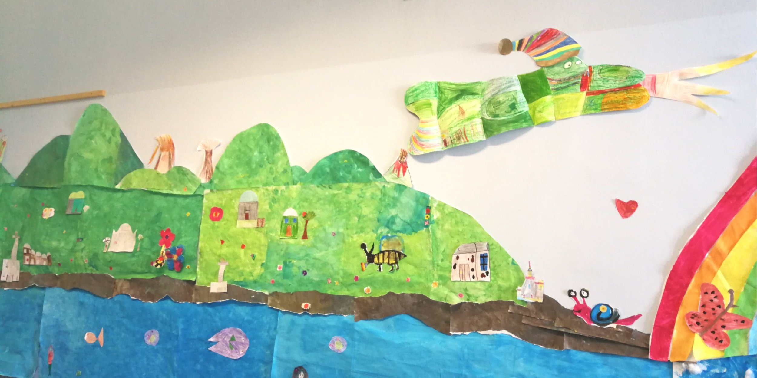 Murales dell'isola di Pantelleria. Realizzato dai bambini con disegni di montagne verdi, dammusi e Ghiussippina draghessa carina che vola sopra l'Ysolah verso l'arcobaleno.