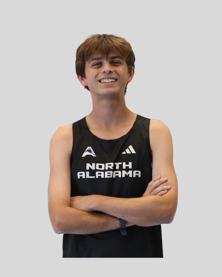 A young man with brown hair smiling, wearing a black athletic tank top with 'North Alabama' printed on it and crossing his arms.