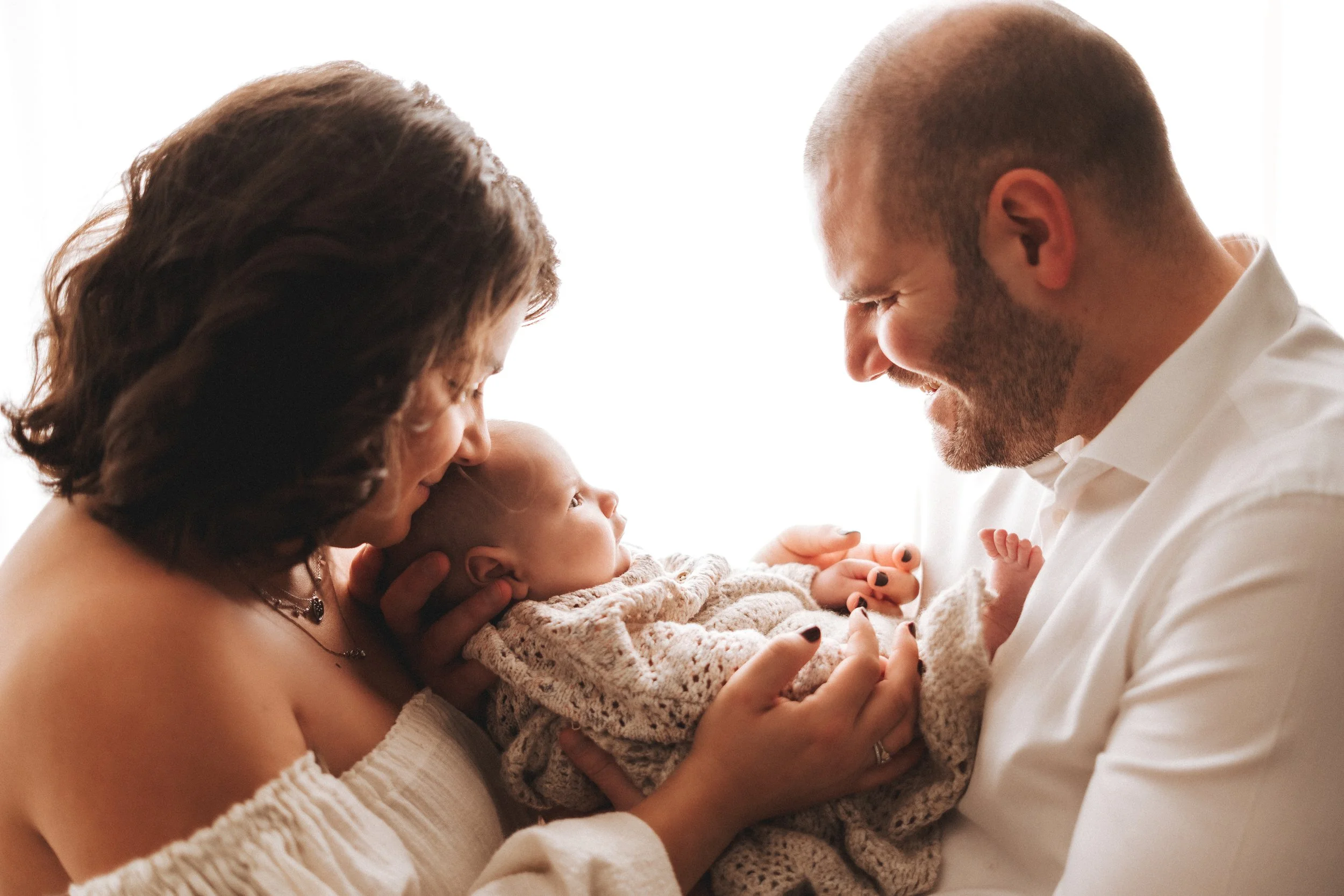 Mamma e papà con neonato in studio durante servizio newborn a Prato.