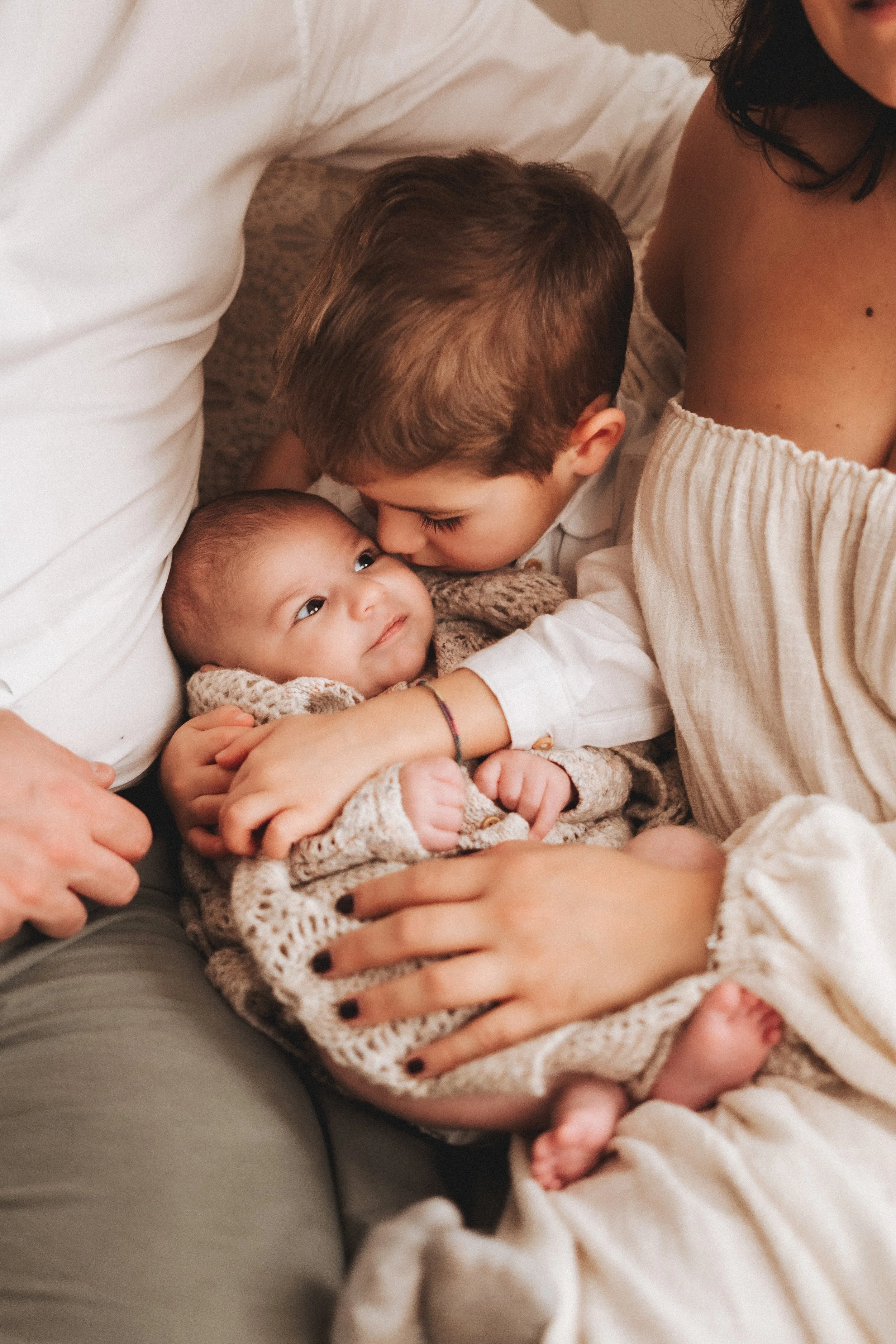 Fratellino che bacia il neonato durante servizio fotografico newborn a Prato.