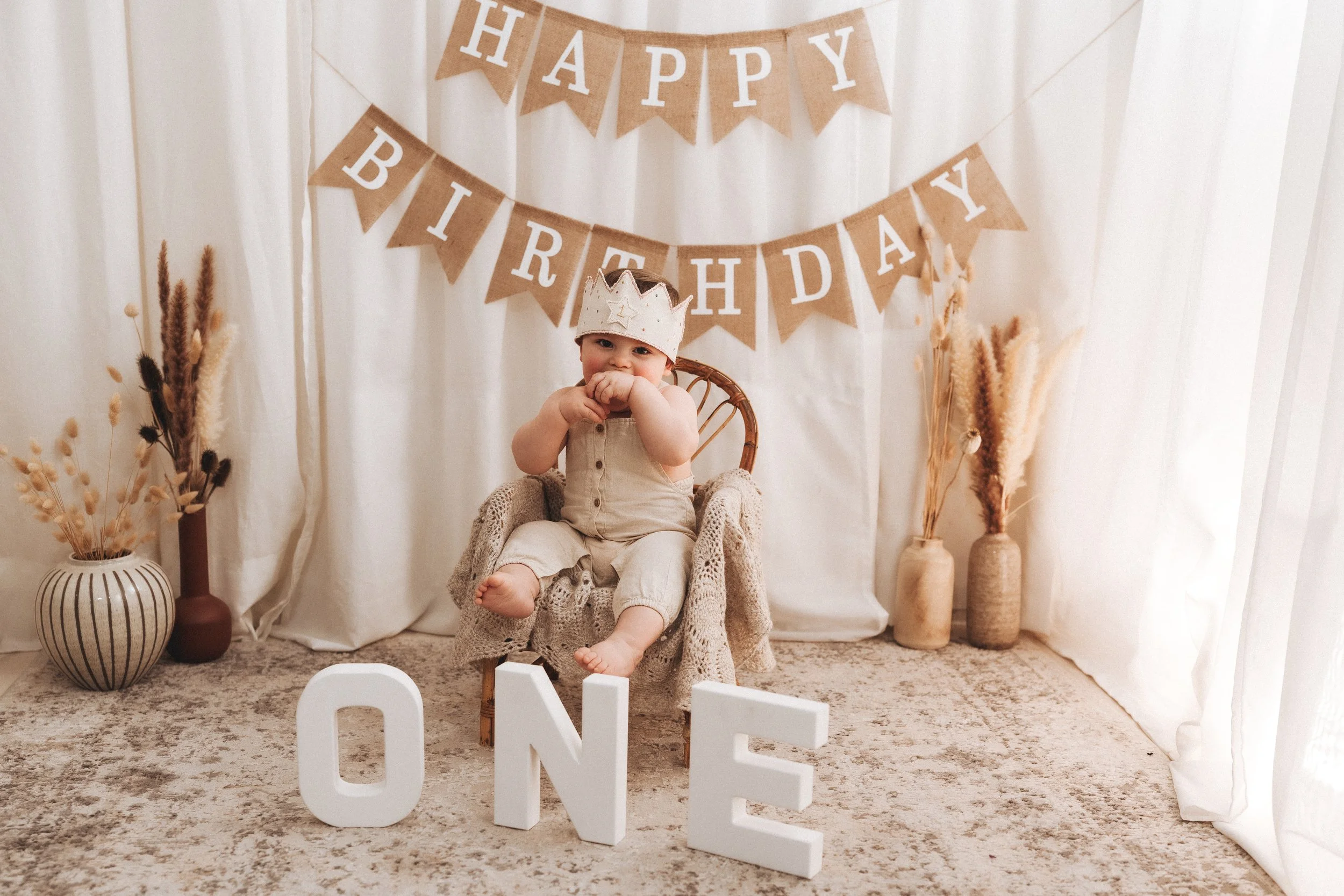 Servizio fotografico smash cake a Prato, Firenze e Pistoia per il primo compleanno, bambino seduto con corona e decorazioni con scritta ONE.