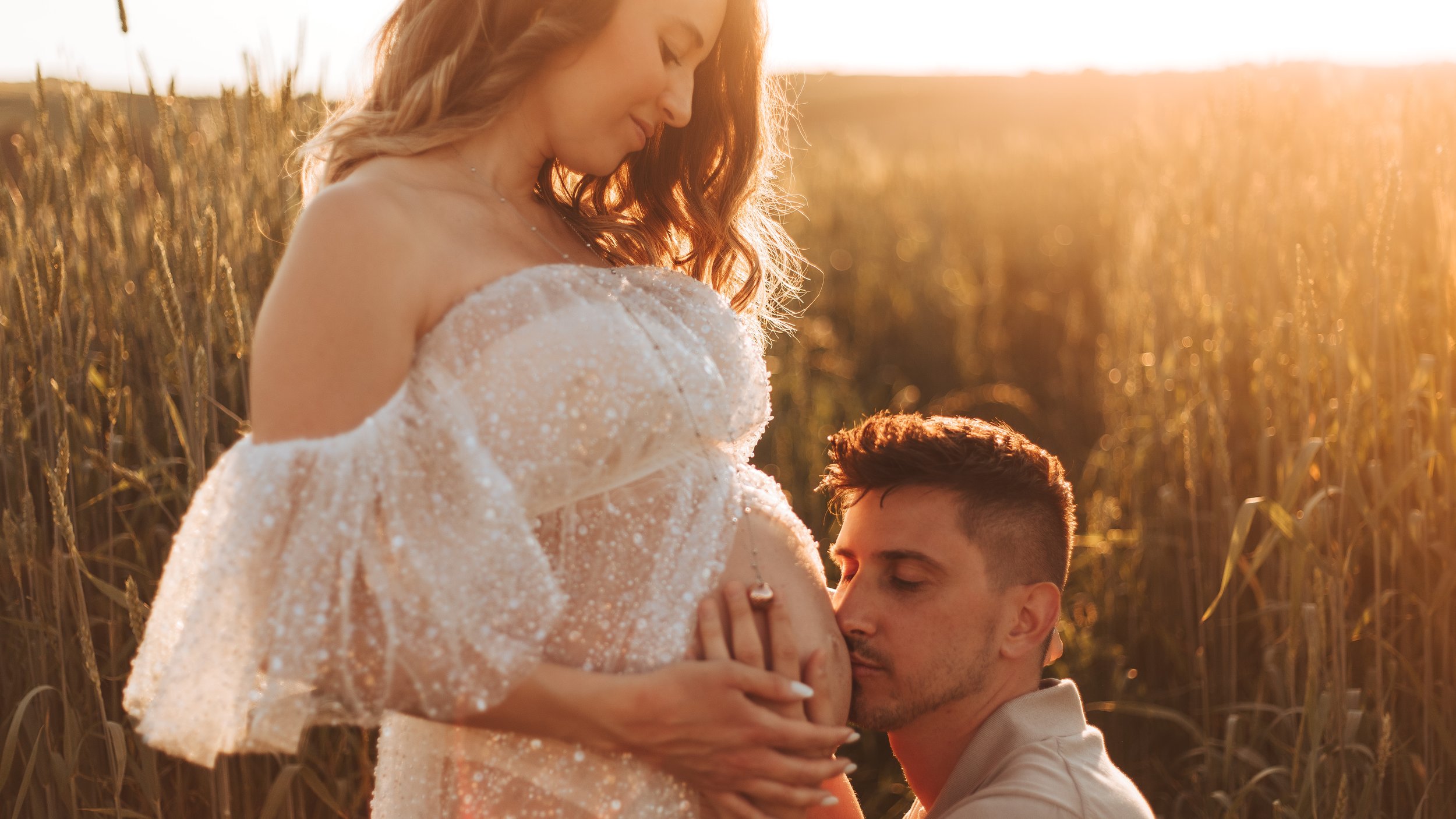 Papà che bacia il pancione al tramonto durante servizio gravidanza a Prato.