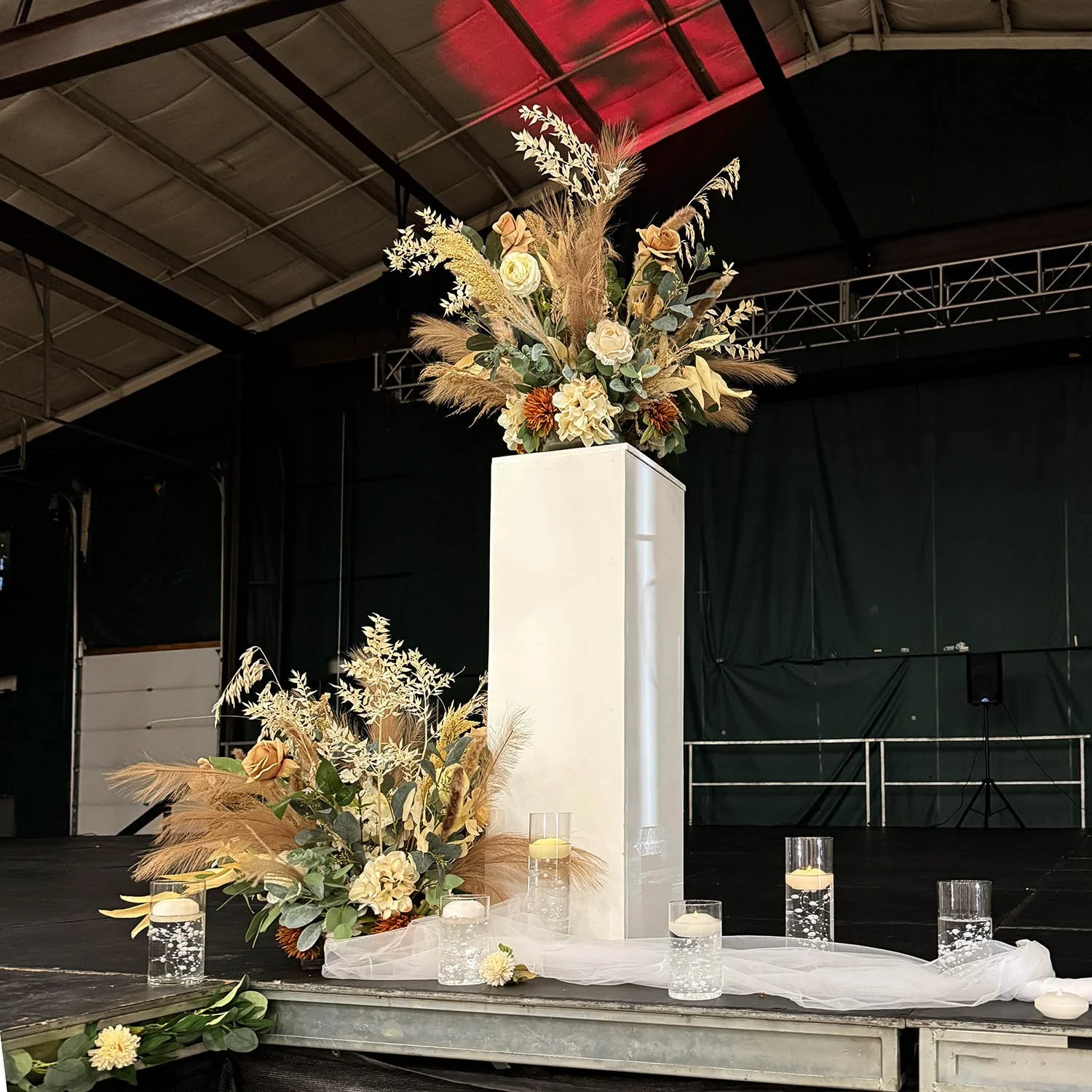 Statement floral arrangements and candle details styled on an event stage