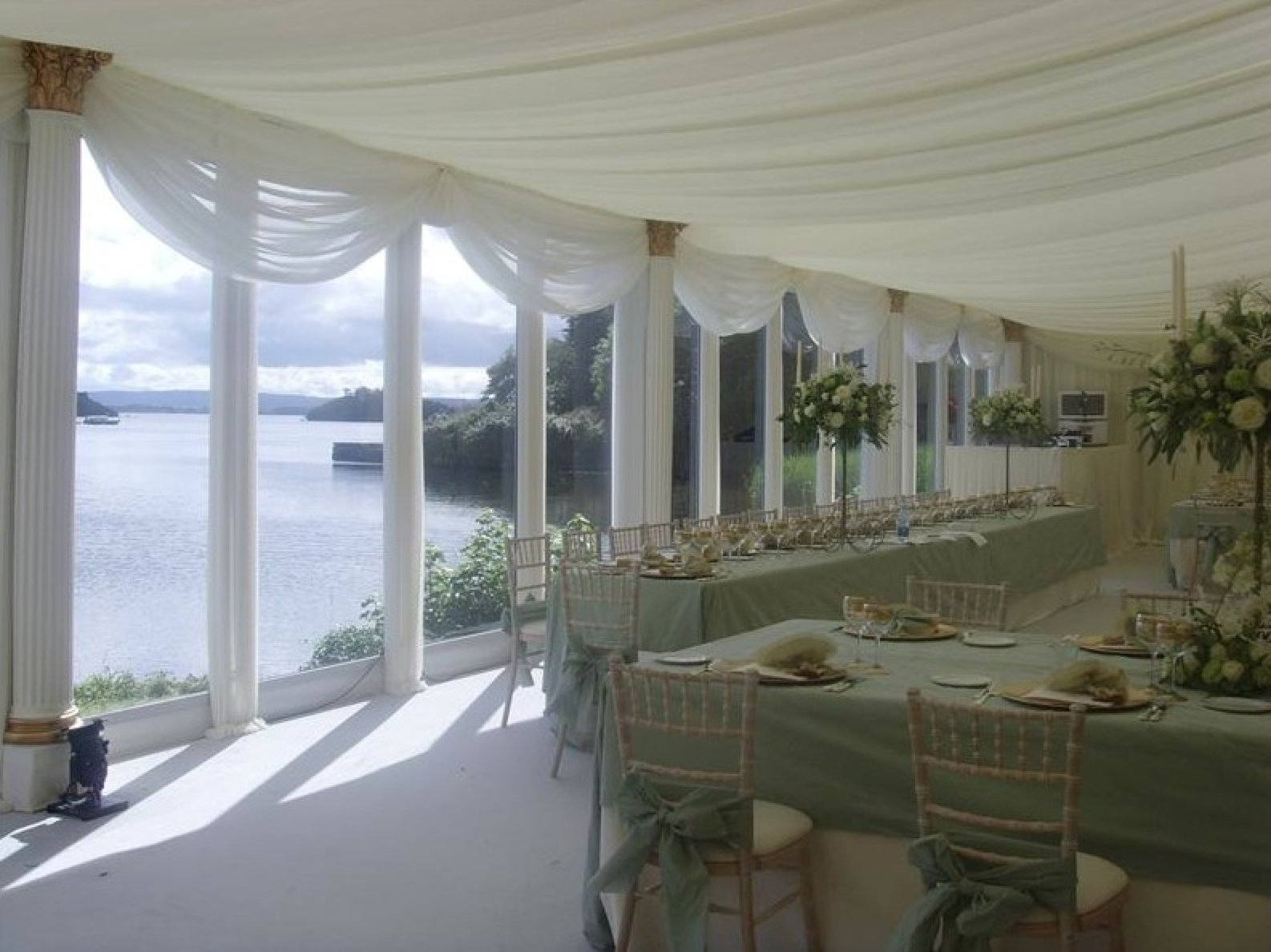 White draped marquee roof with a lake view