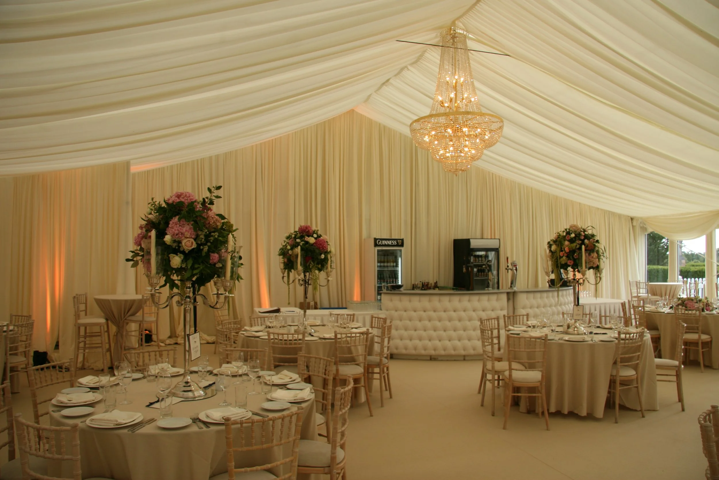 Ivory Draped marquee roof with chandeliers and curved bar