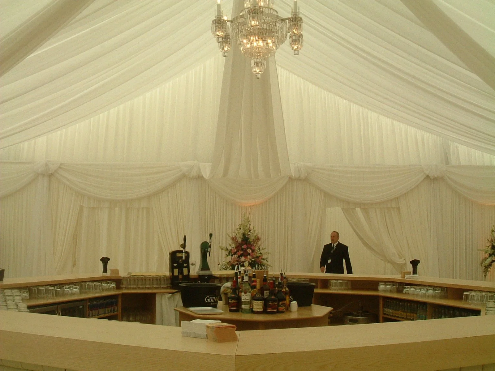 Ivory Draped marquee roof with chandeliers and curved bar