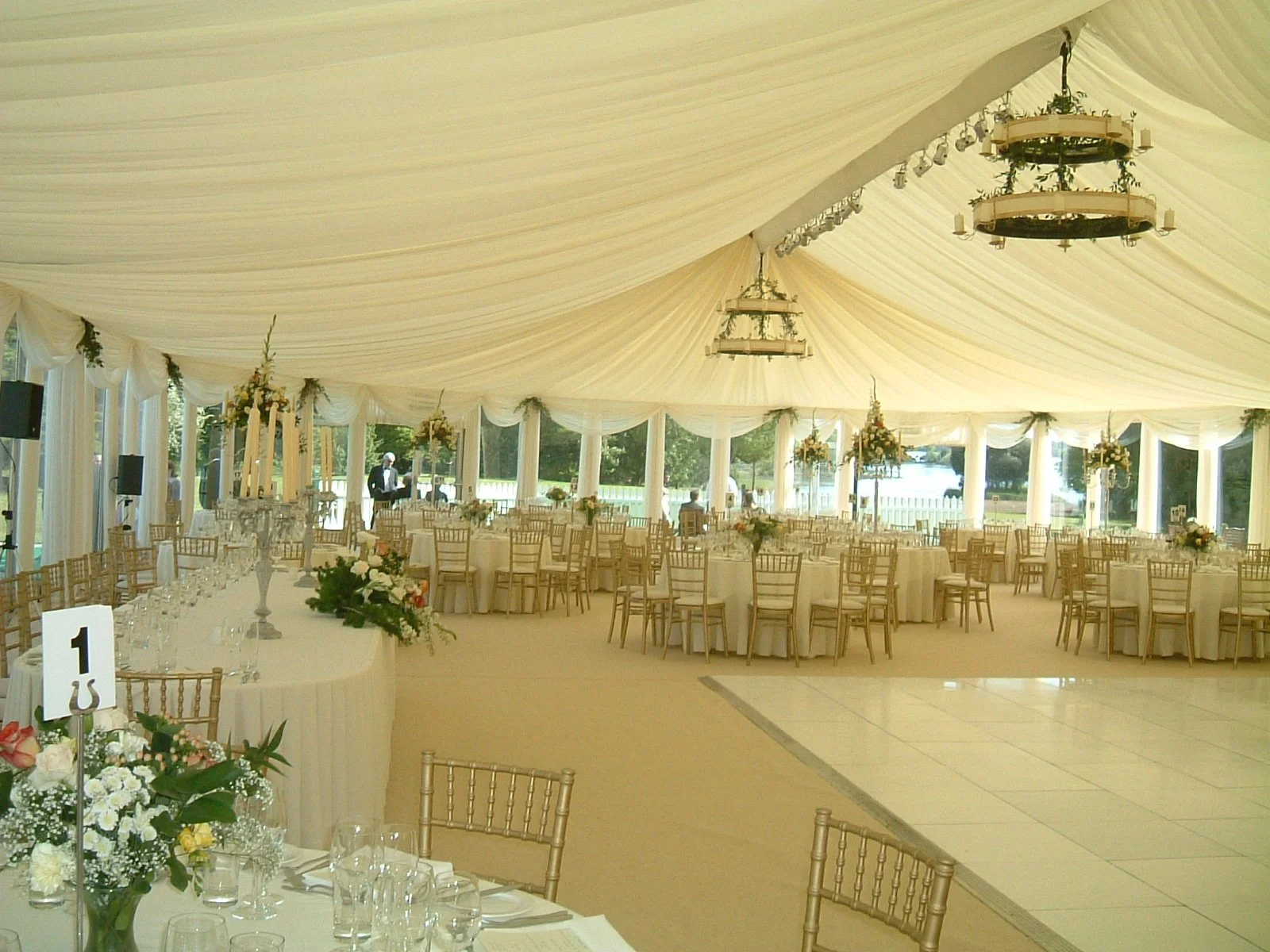 Ivory Draped marquee roof with chandeliers and white dancefloor