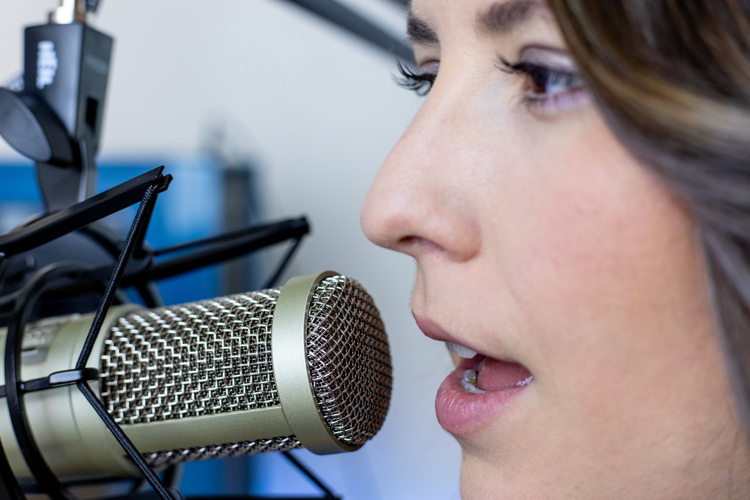 woman speaking into microphone podcasting