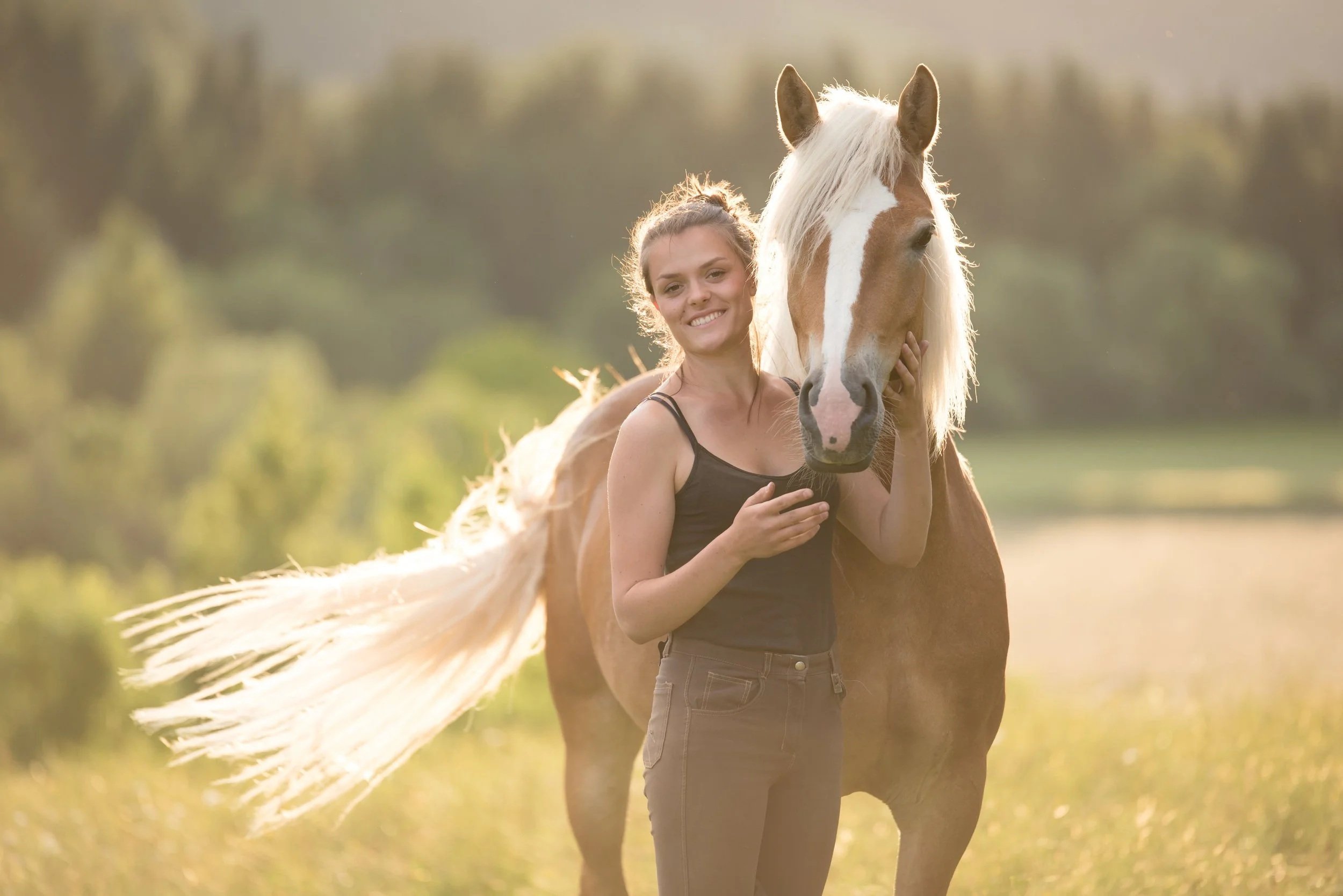 Viktoria Moser steht neben ihrem Pferd auf einer Wiese im Murtal bei Sonnenuntergang